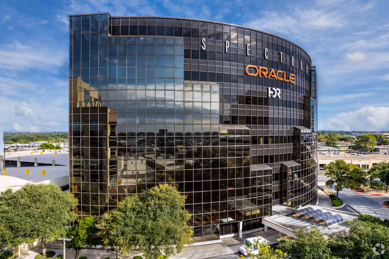 A curved glass office building with Oracle signage and reflective windows.