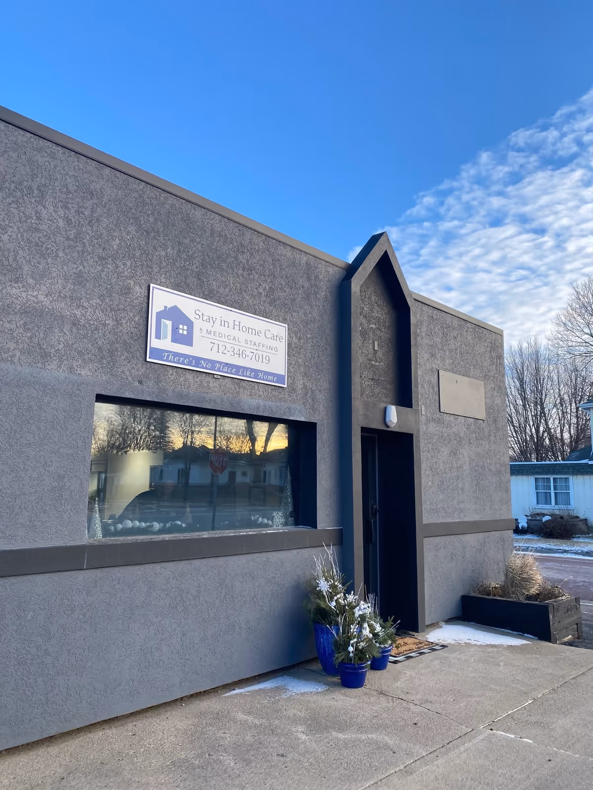 Exterior view of Stay in Home Care & Medical Staffing building with sign, window, and plants.