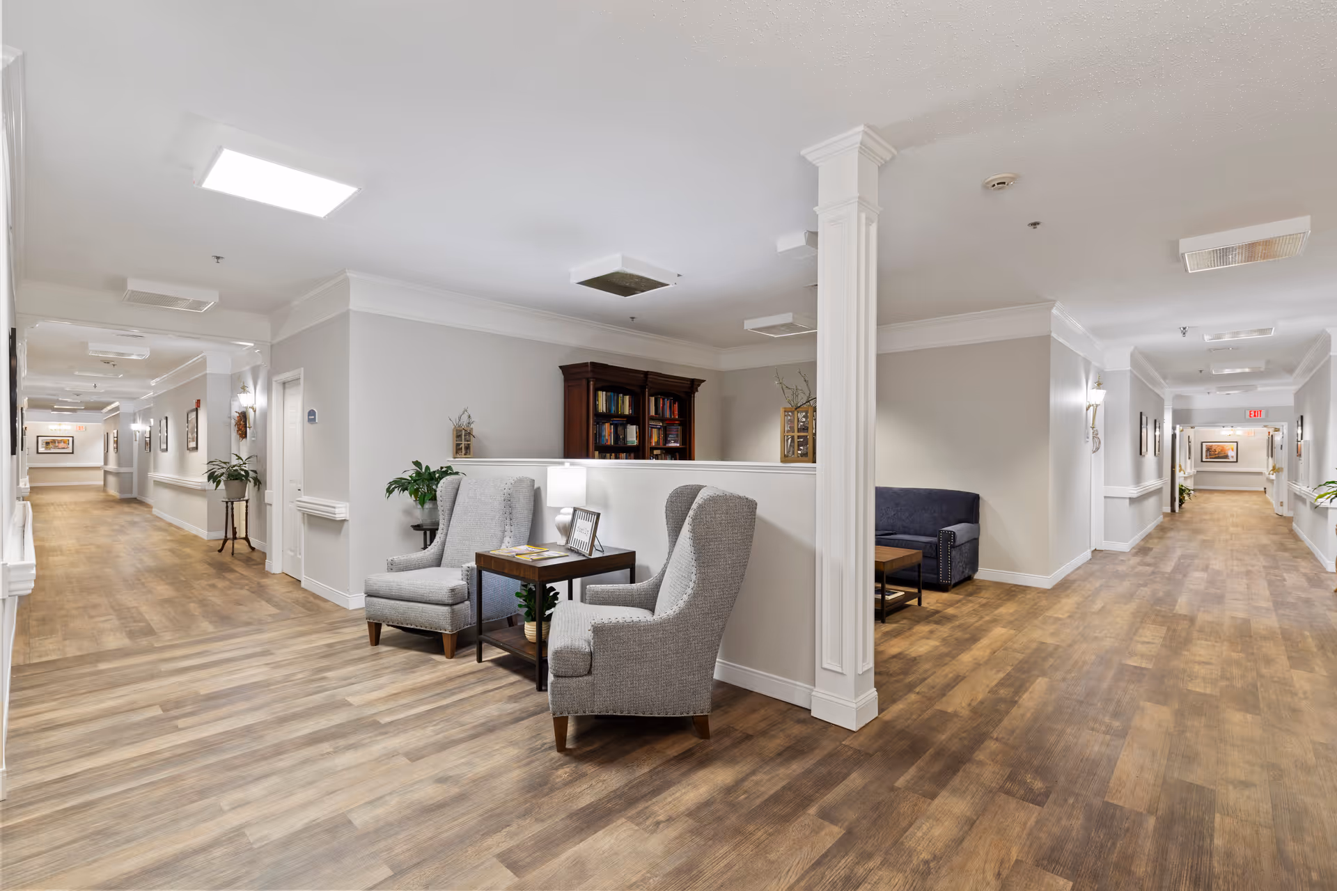 Bright senior living lobby with seating, a bookshelf, and a dividing column.