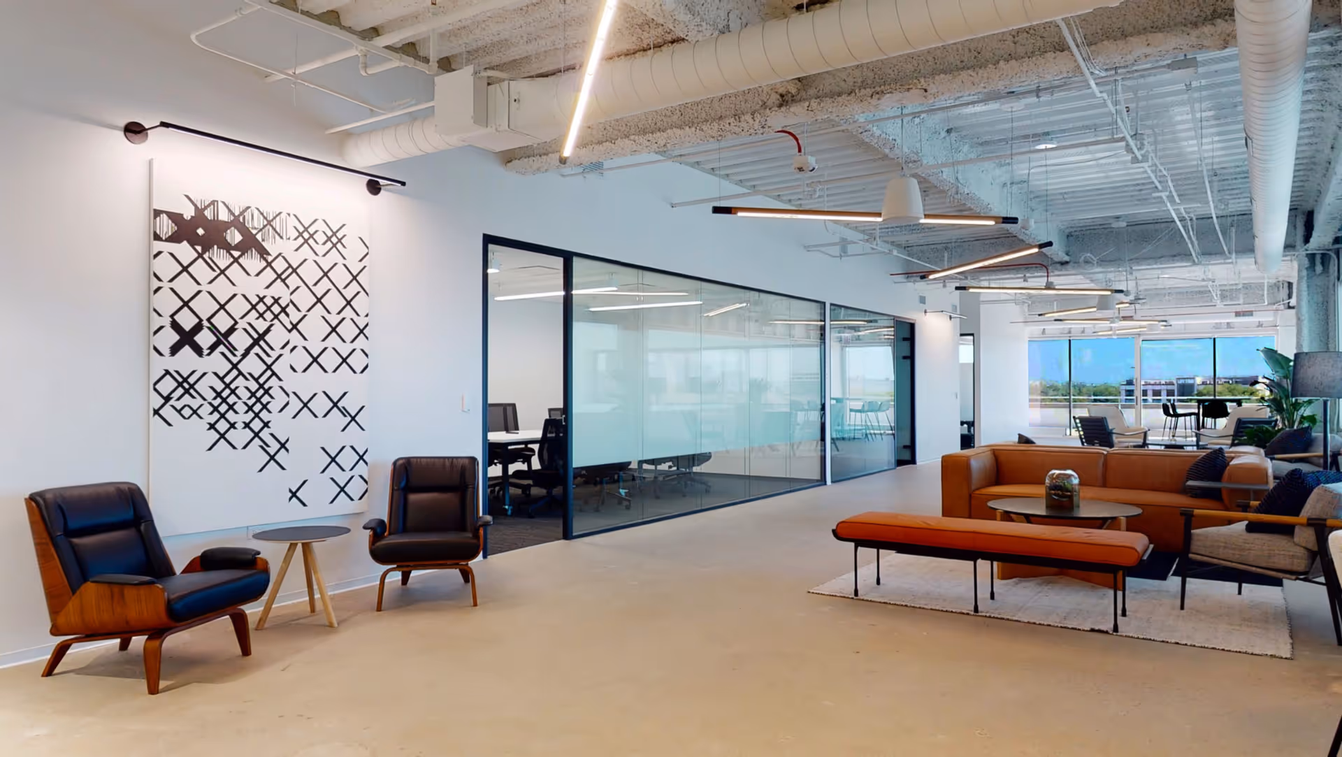 Modern lounge area with brown seating, glass walls, and contemporary decor in a bright facility.