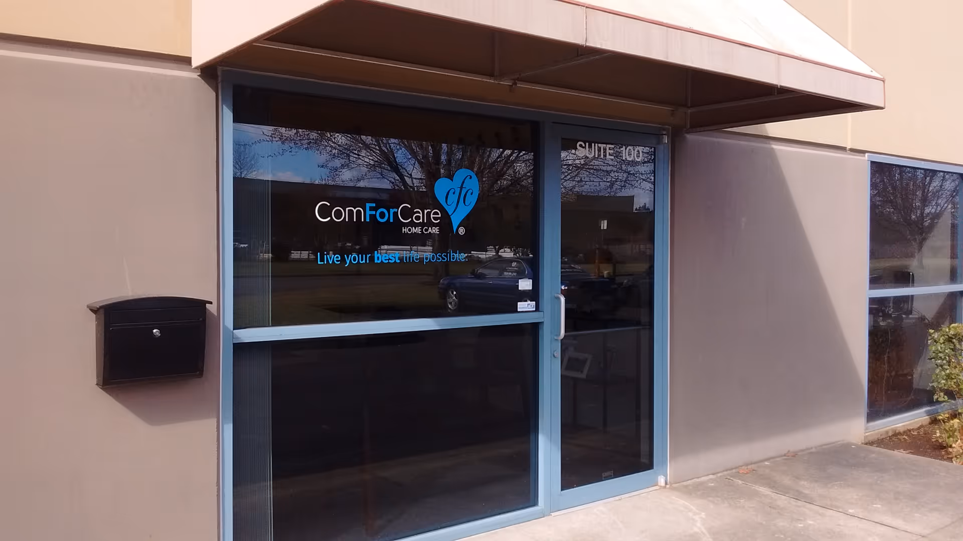 Exterior entrance of ComForCare Home Care with glass doors and a blue frame.
