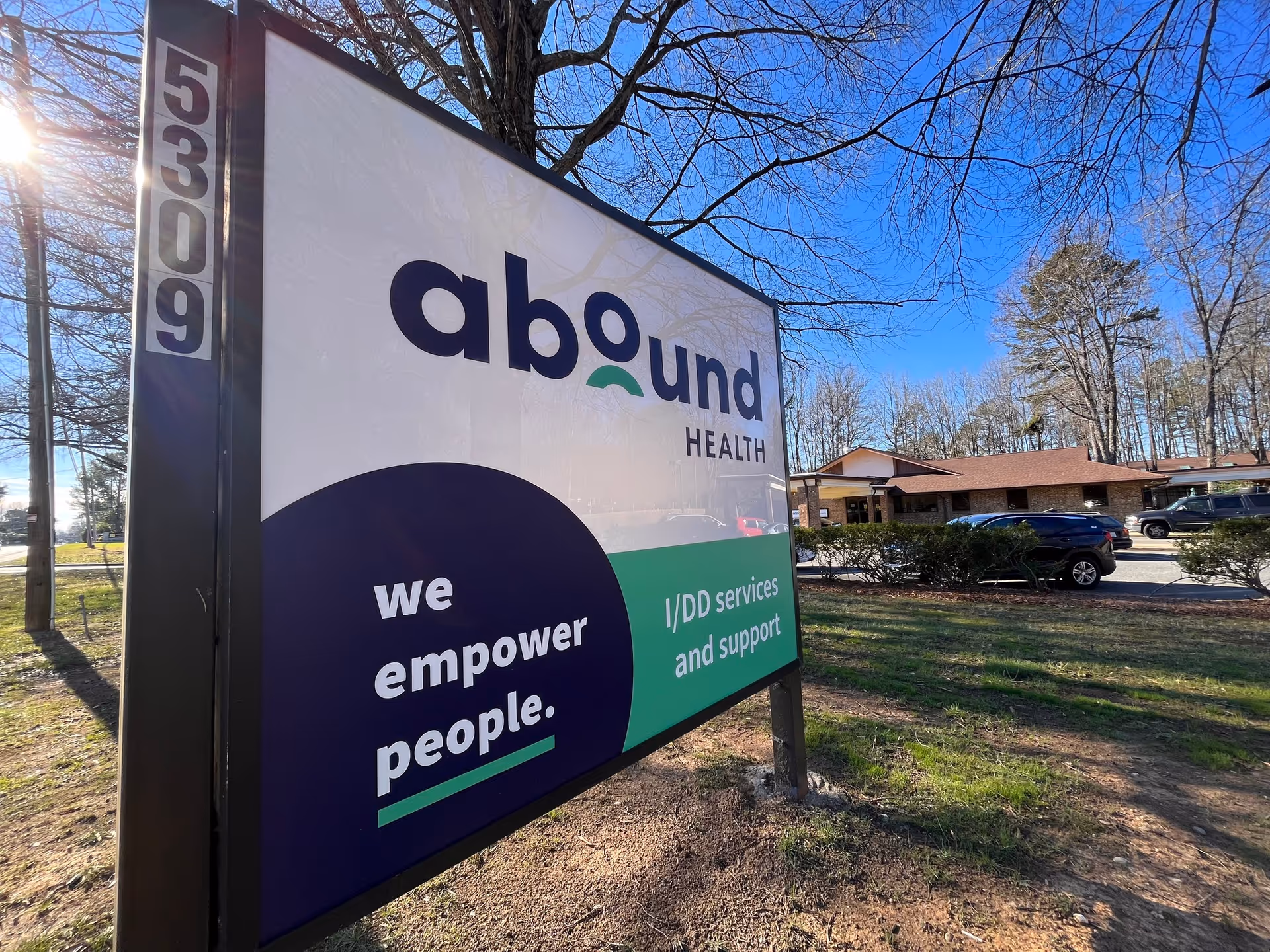 Exterior view of Abound Health facility with large roadside sign and parked cars