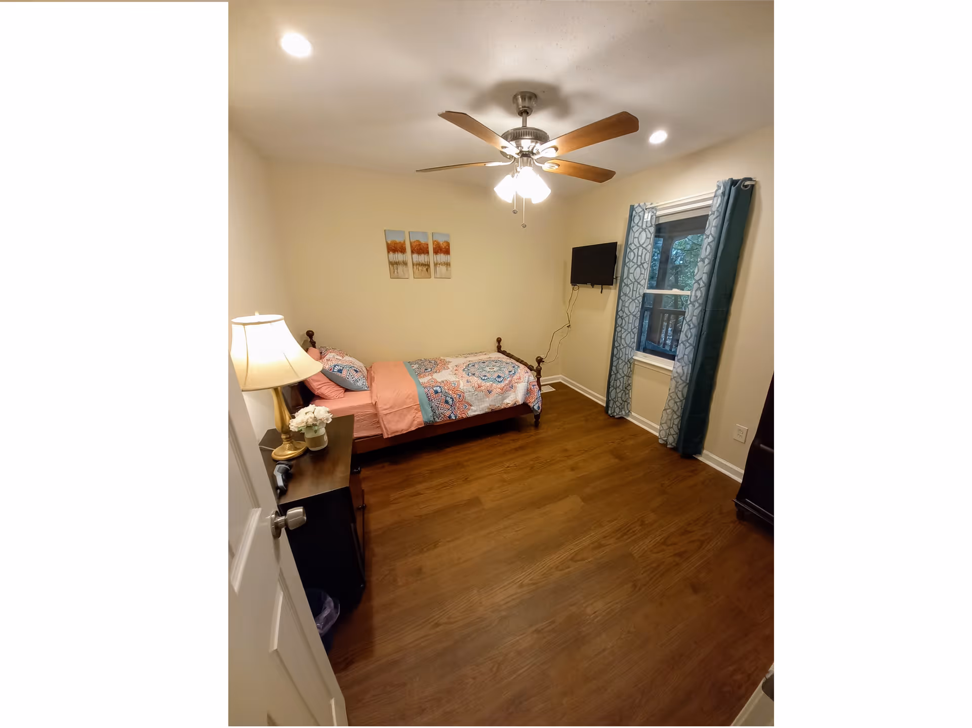 Cozy senior living bedroom with bed, dresser, ceiling fan, and window with curtains.