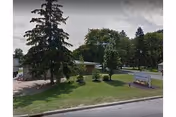 Exterior view of Vaimar Suites II grounds with trees, lawn, and a sign.