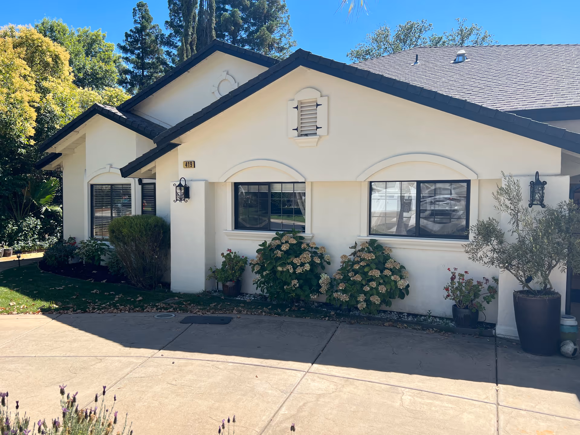 Single-story beige senior care building with arched windows and landscaped front yard.