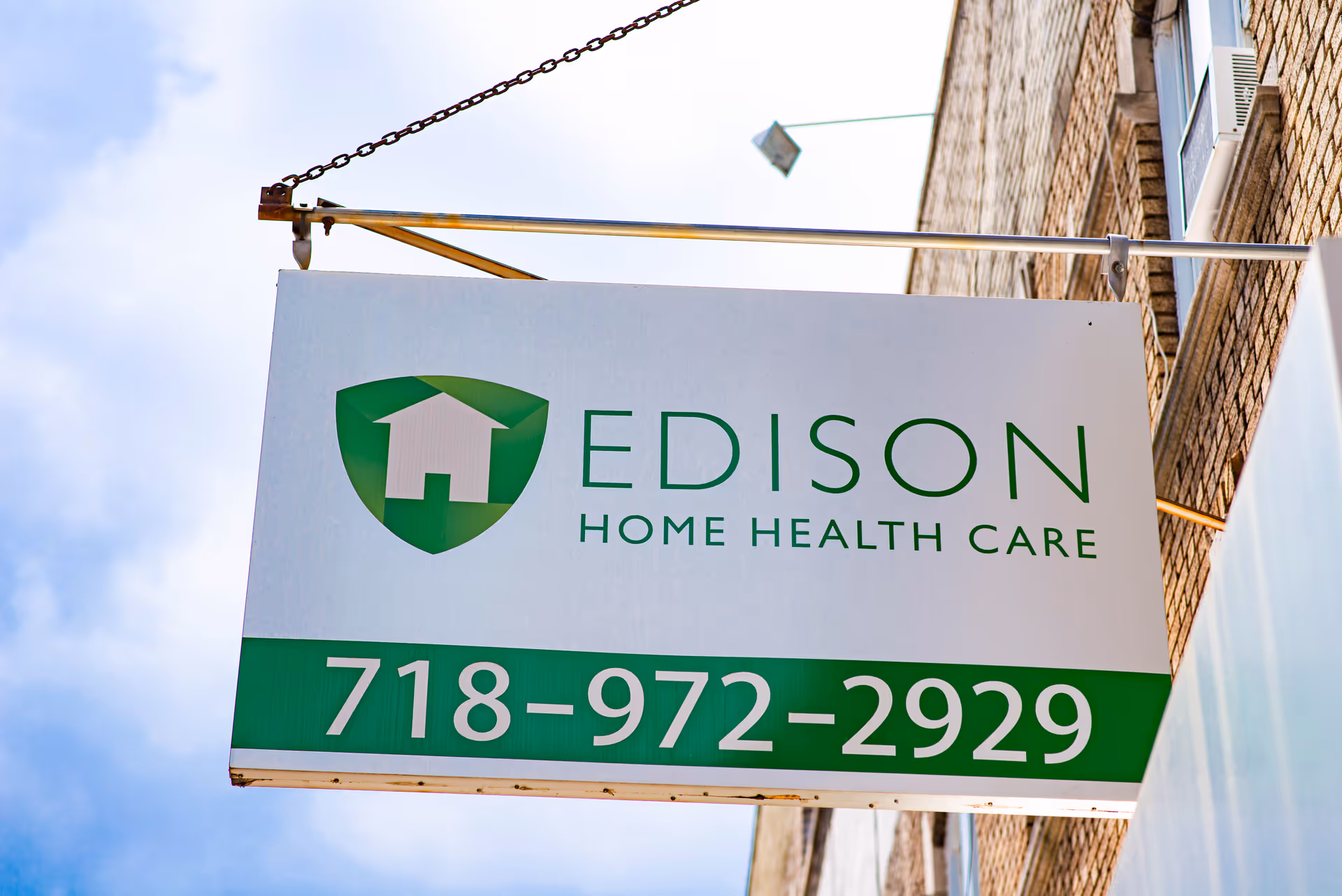 Exterior sign for Edison Home Health Care hanging from a brick building facade.