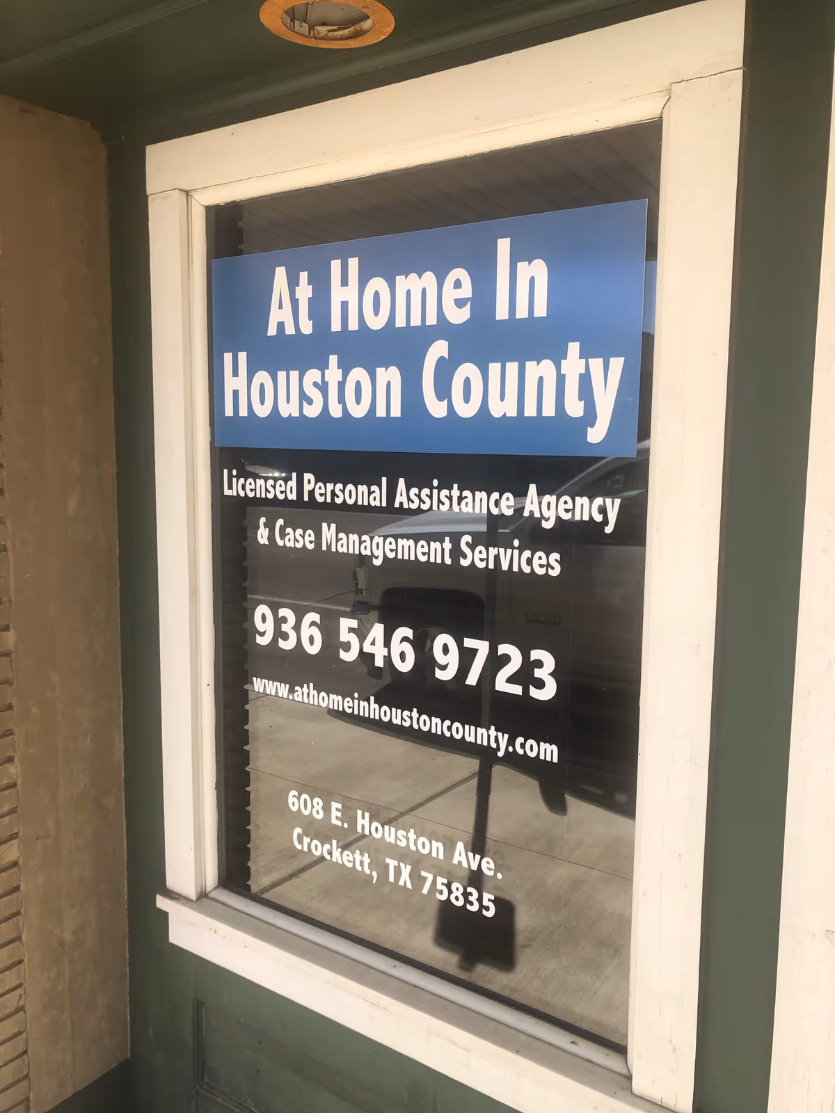 Storefront window with a blue sign reading At Home In Houston County.