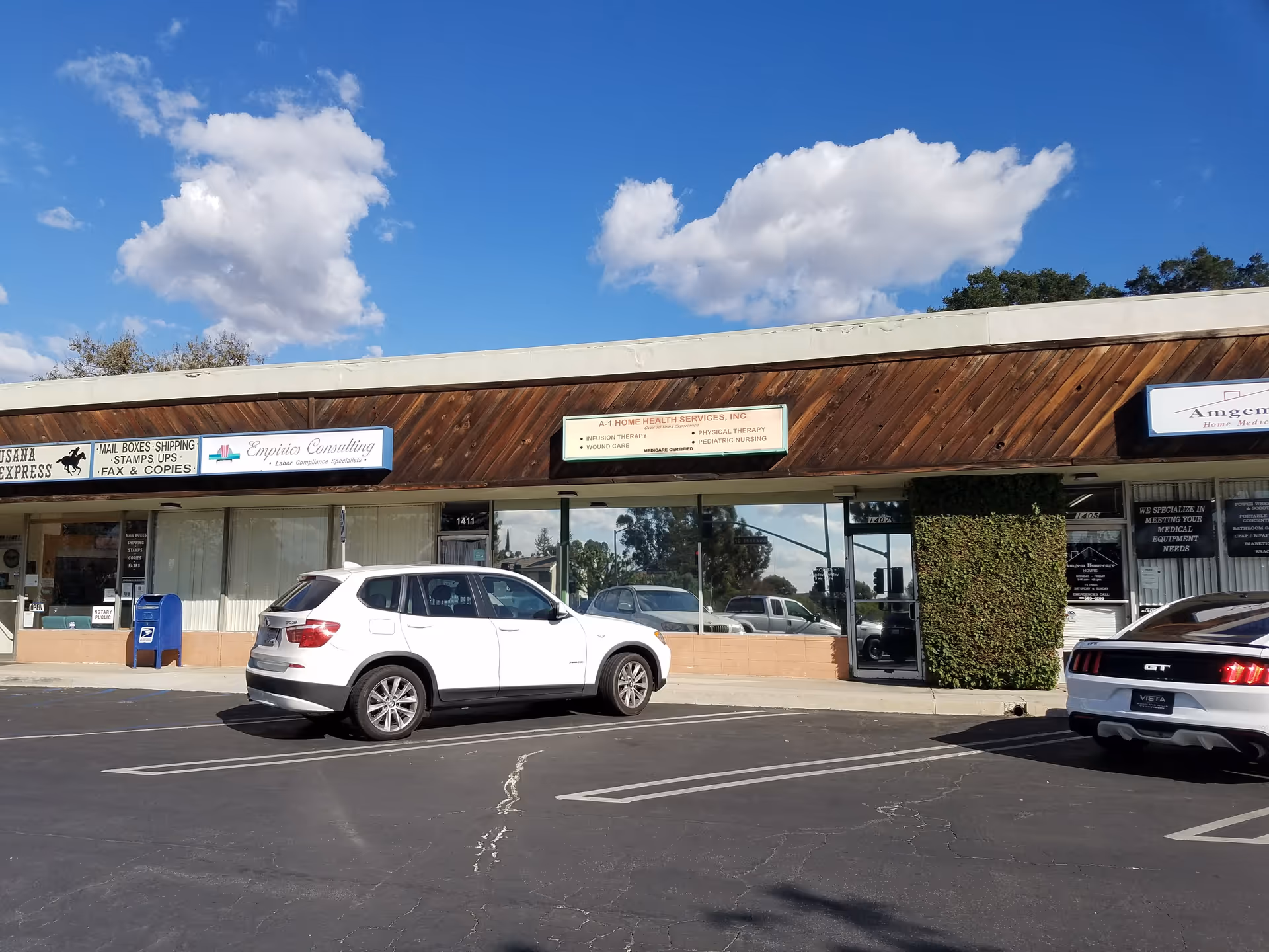 Exterior storefront row with A-1 Home Health Services, Inc. sign and parked cars against blue sky.