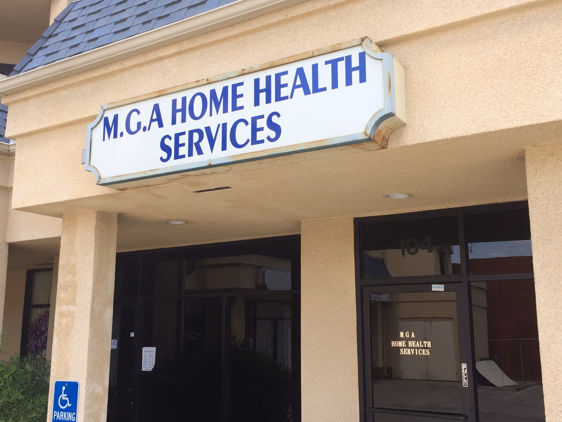Beige building exterior with a large sign reading M.G.A Home Health Services above entrance.