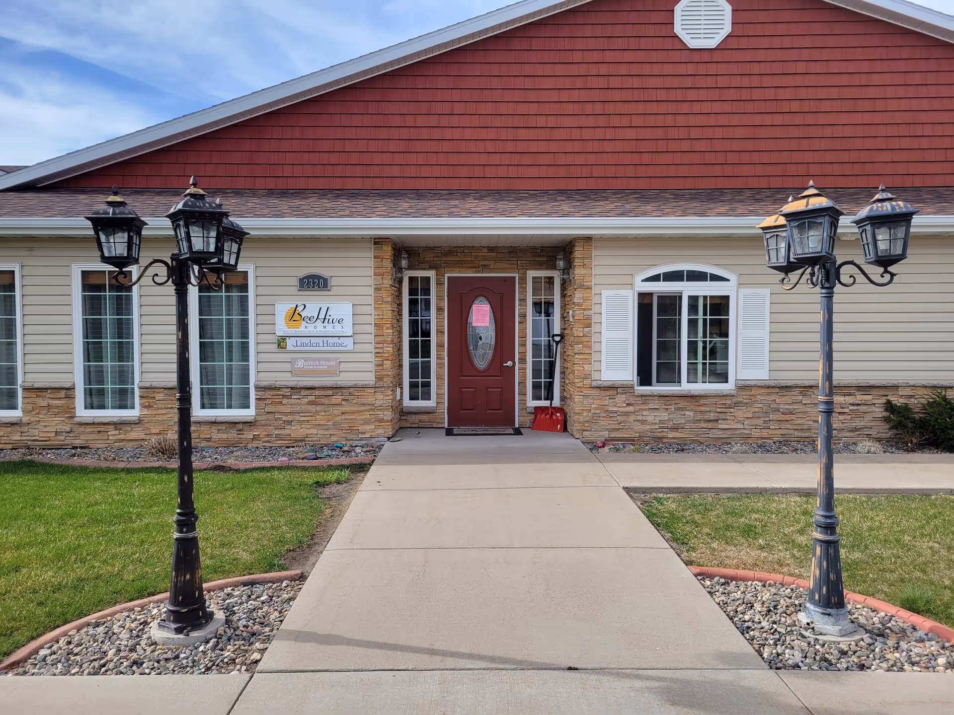 Front exterior of BeeHive Homes of Great Falls with red entry door and lamp posts.