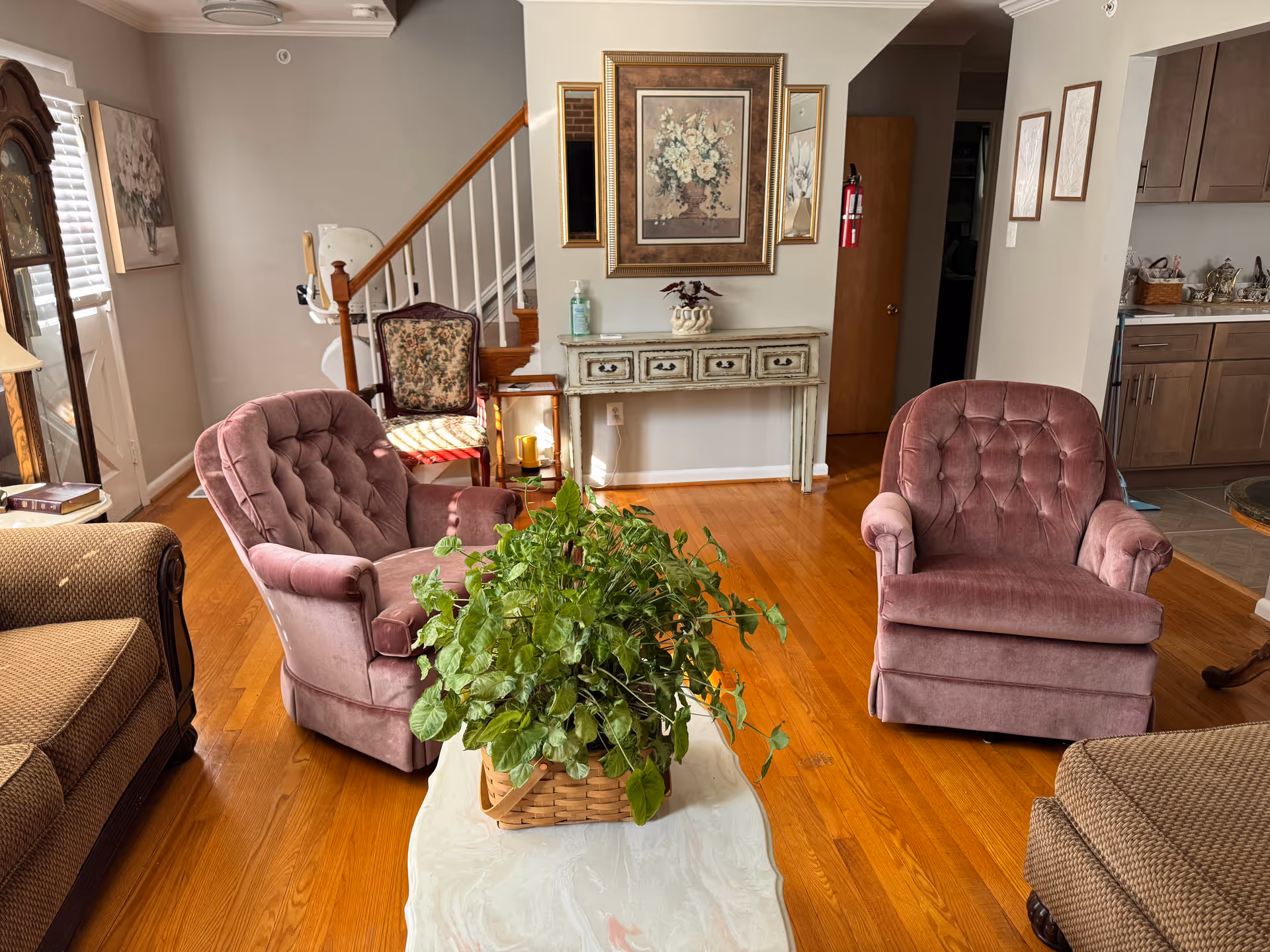 Cozy living room in an assisted living home with pink chairs and greenery.