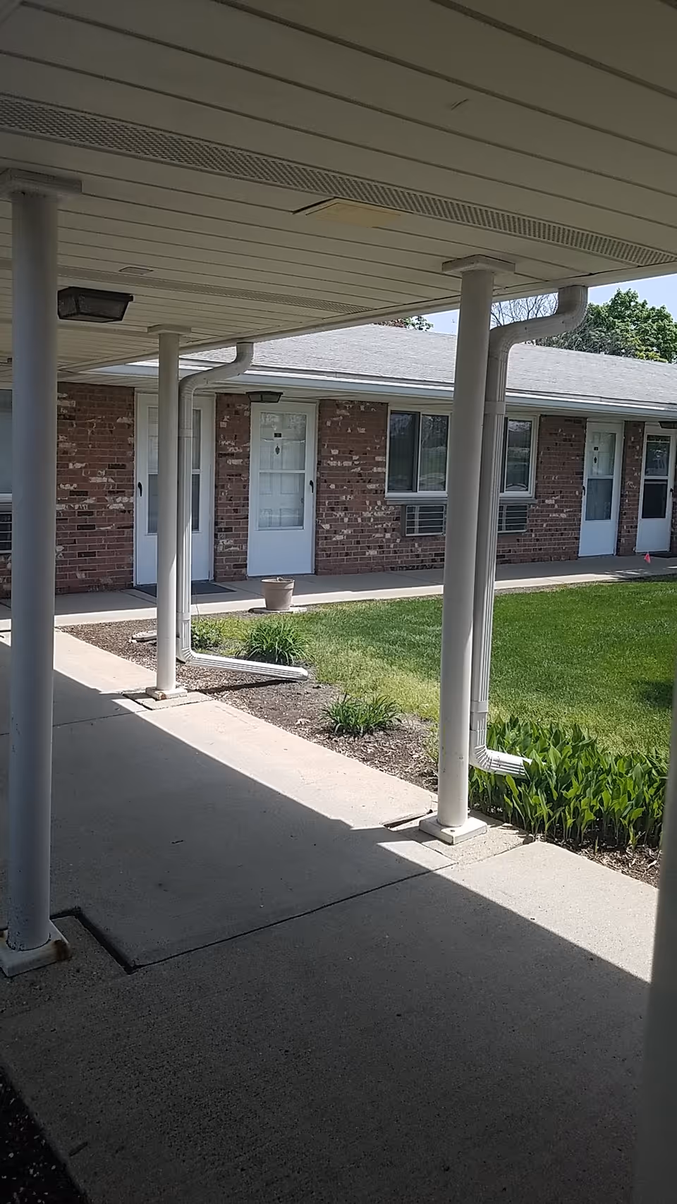 Exterior view of Clinton Villa facility with brick building, doors, columns, and lawn.