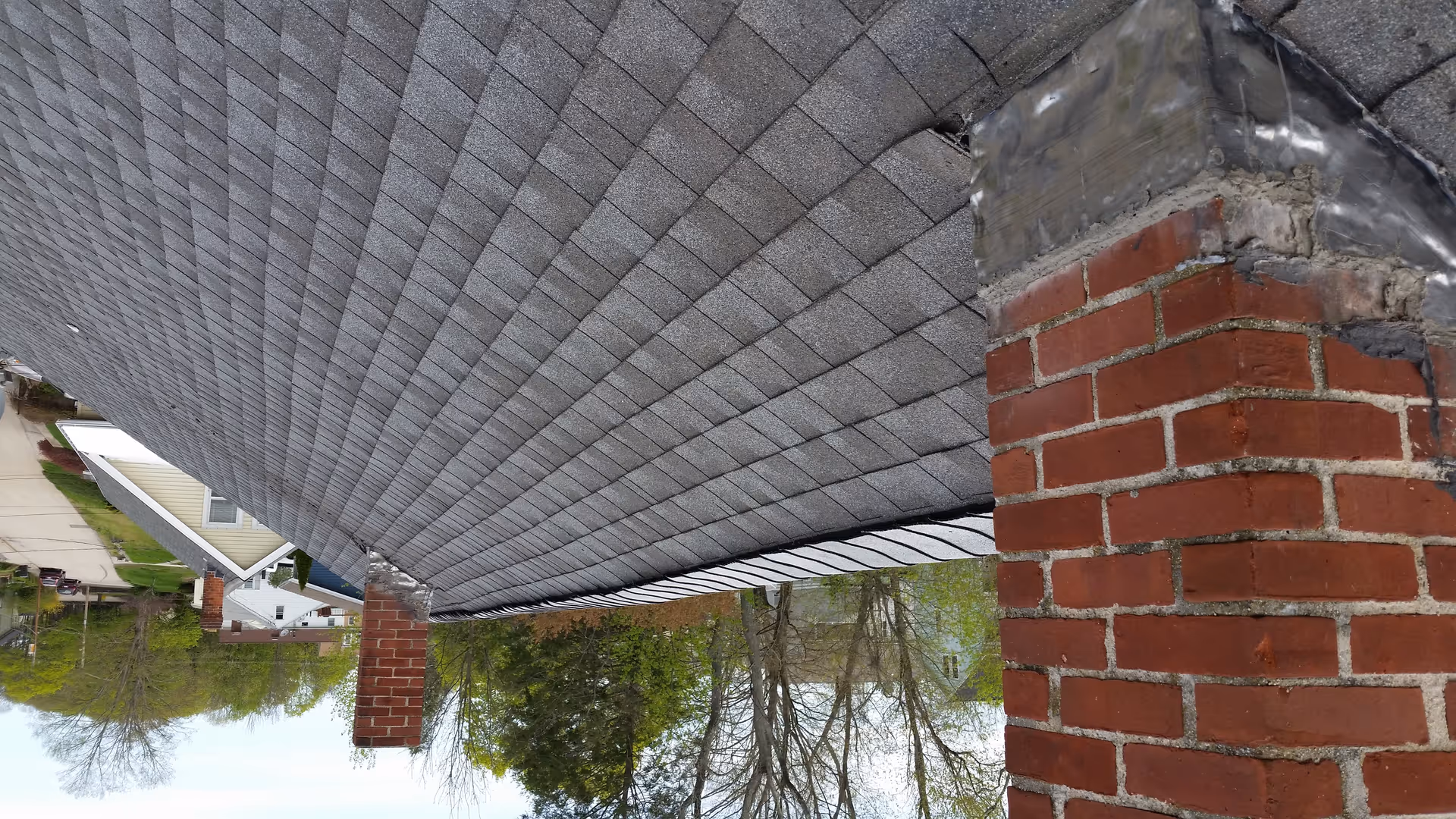 Exterior view of a brick column supporting a roof overhang along a sidewalk.
