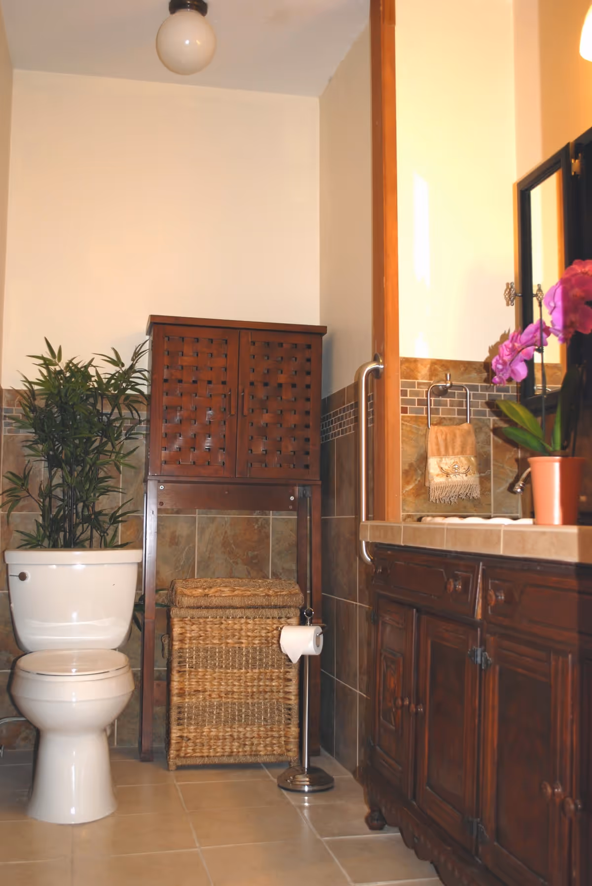 A compact bathroom featuring a wooden cabinet, wicker basket, toilet, and sink vanity.