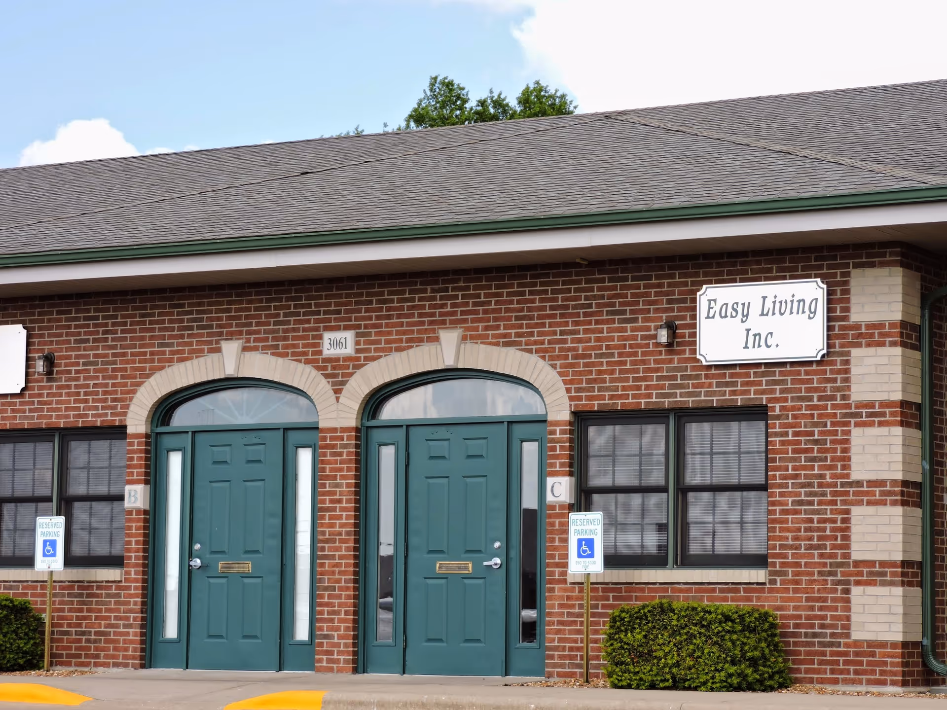 Brick building exterior with two green arched doors and Easy Living Inc. sign.