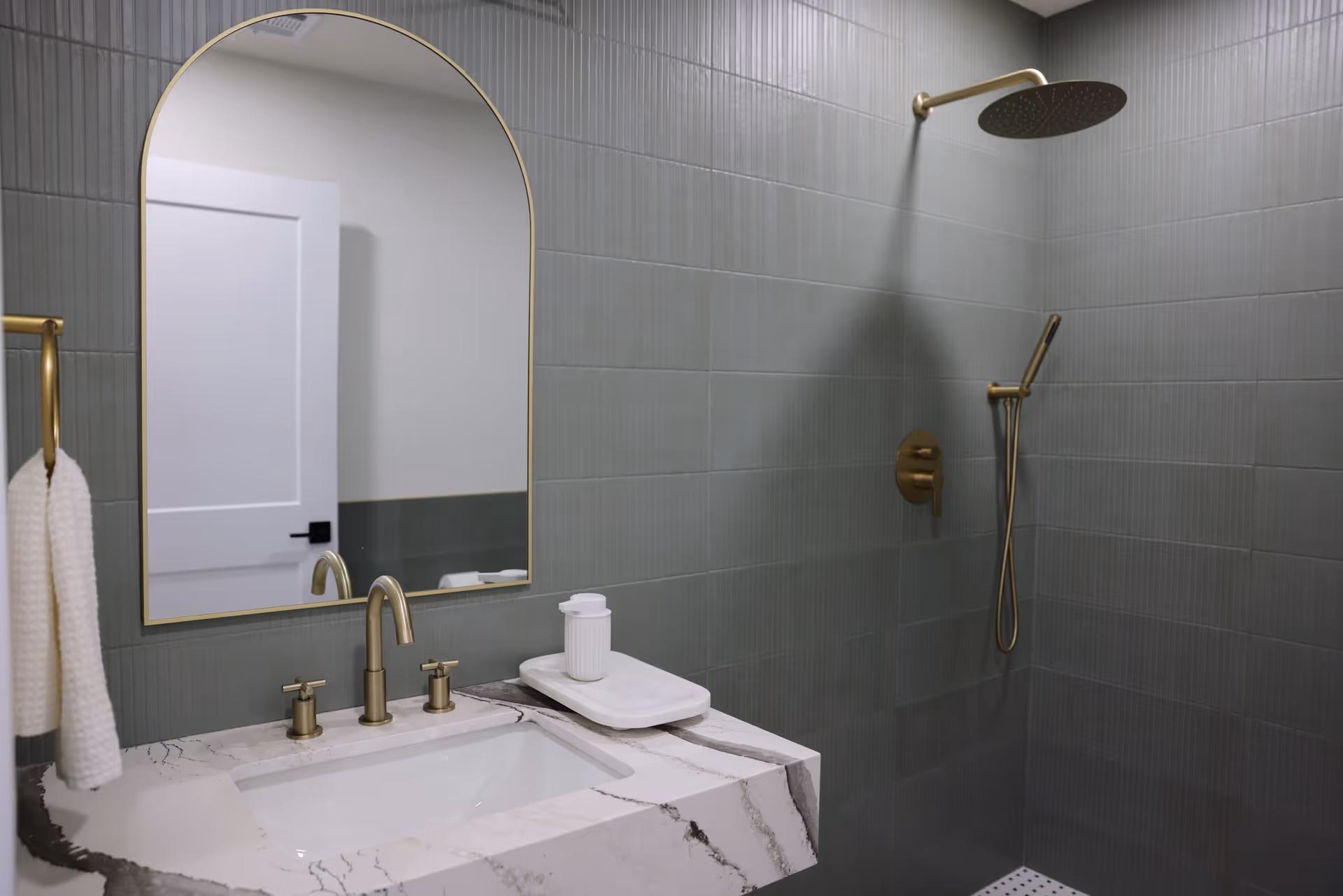 Modern bathroom with marble sink, gold fixtures, and a spacious walk-in shower.