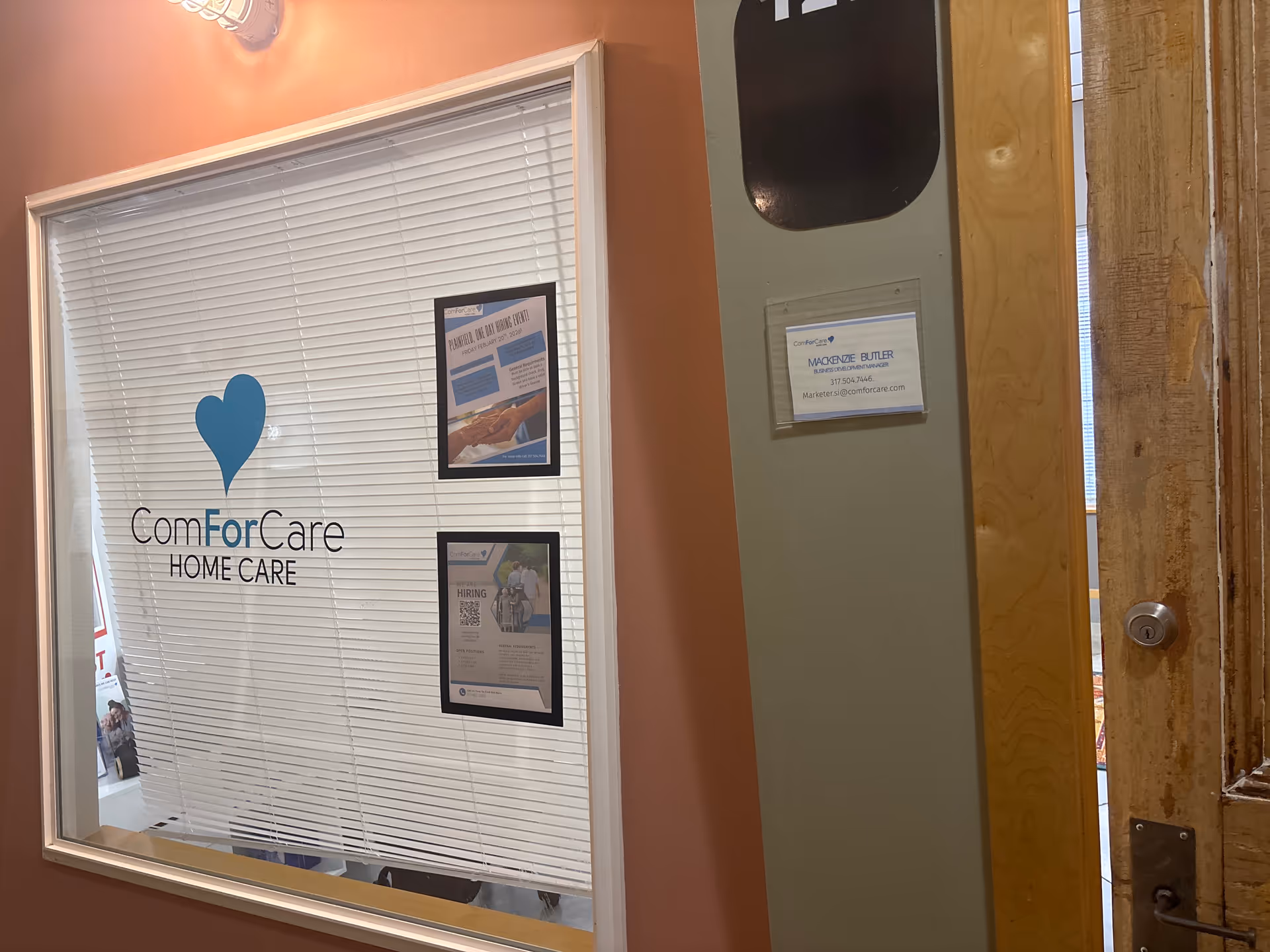 Interior window with ComForCare Home Care logo and posted notices on blinds.