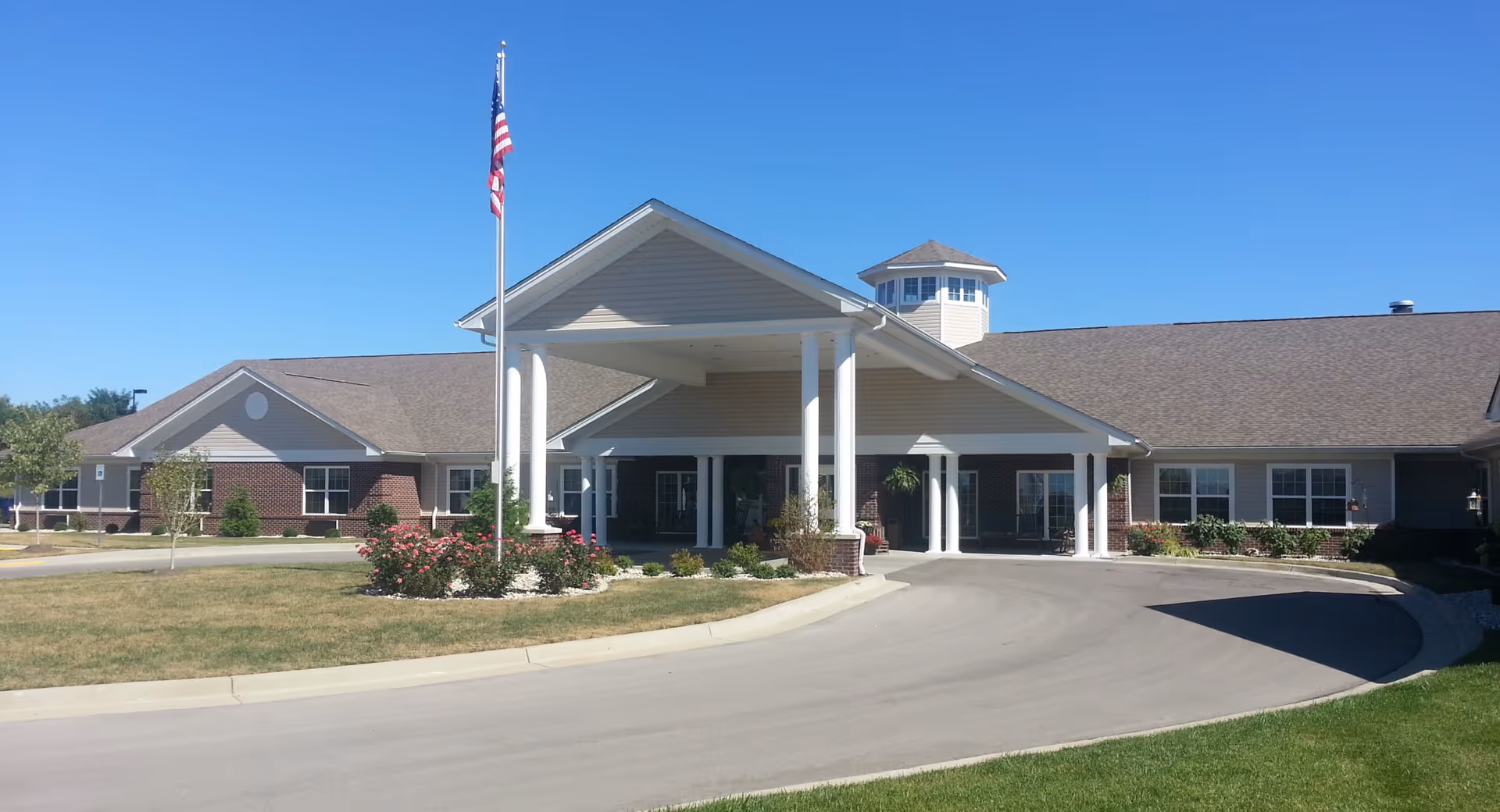 Exterior view of The Willows at Citation with a covered entrance, flagpole, and landscaped grounds.