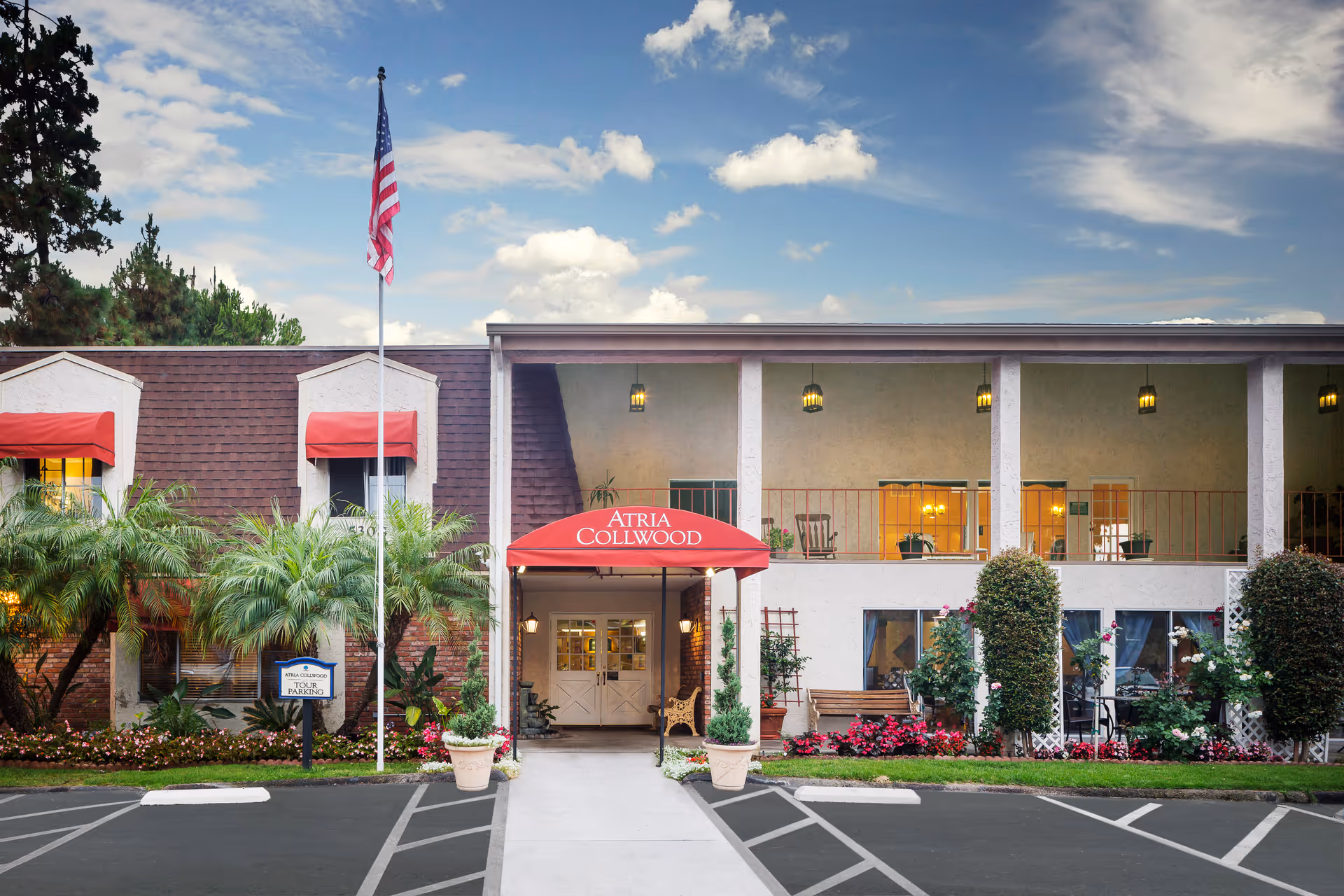 Exterior of Atria Collwood with red entrance canopy, flag, and landscaped walkway