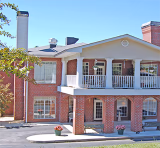 Red brick senior living facility exterior with a covered porch and planters.