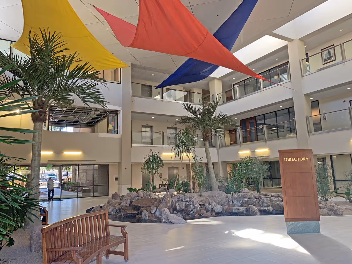 Interior atrium of SPG Virtual Care facility with palm trees and colorful canopies.