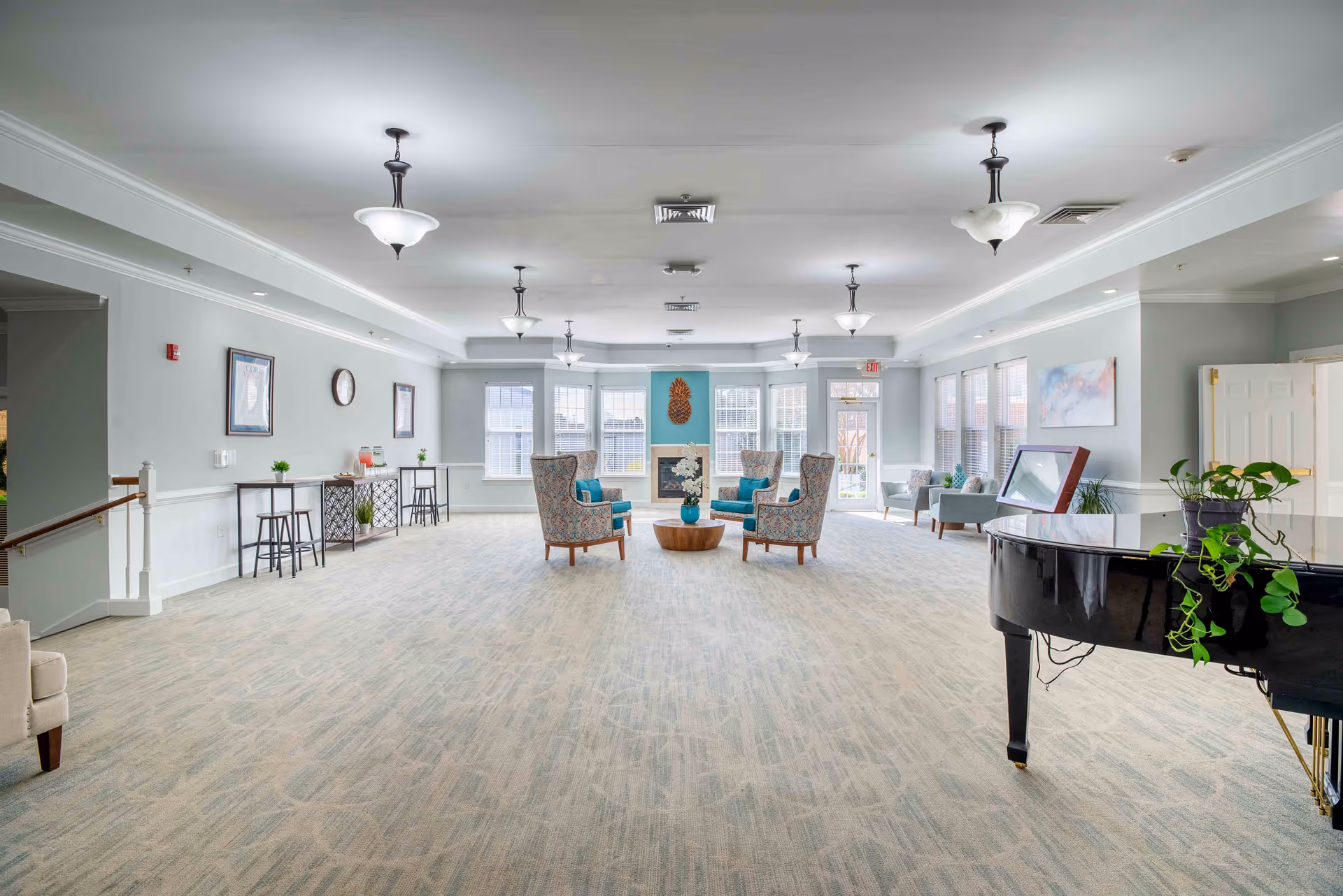A bright, spacious common living area with seating, a piano, and large windows.