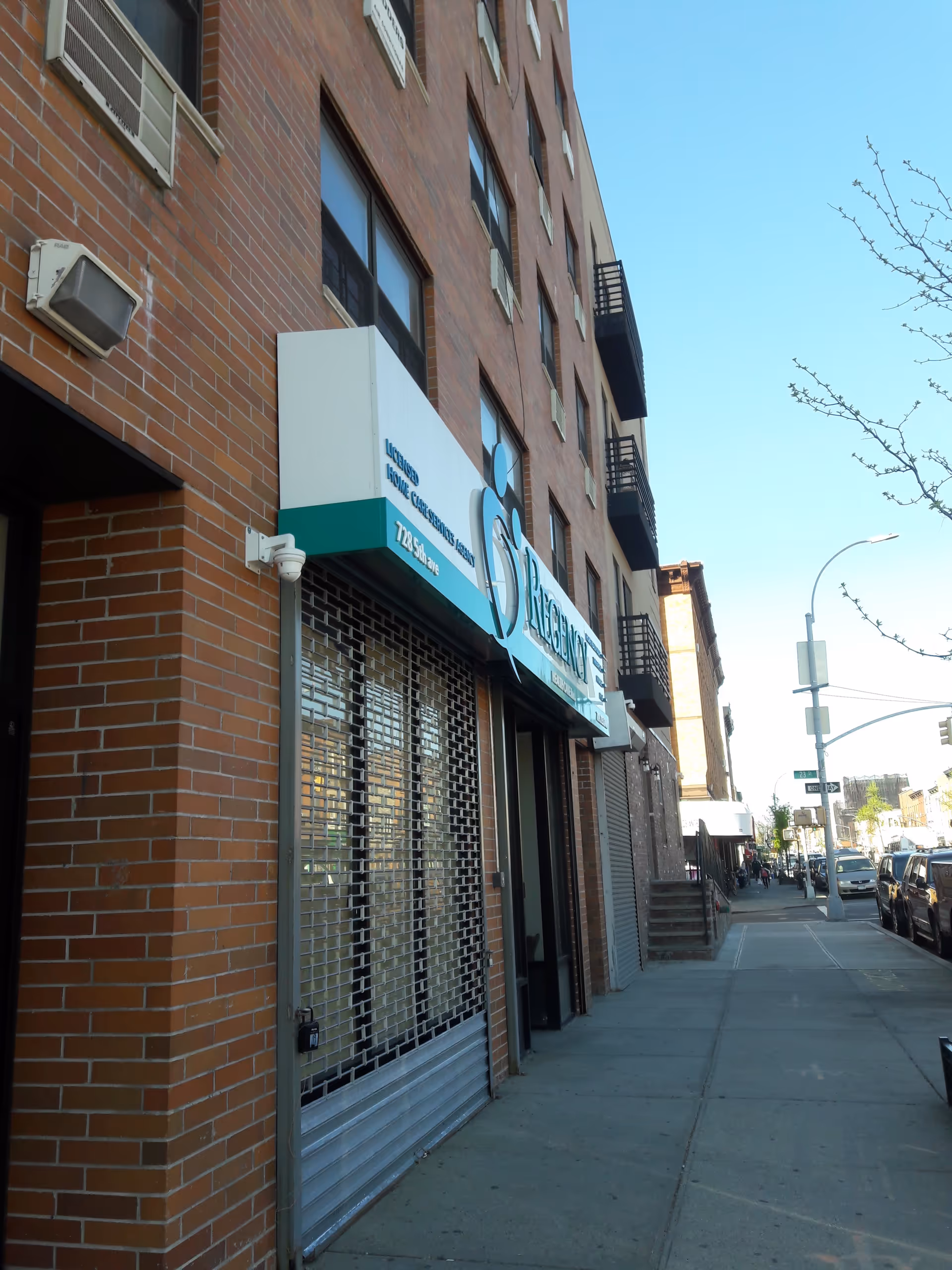 Brick building storefront with Regency Health Care sign along a city sidewalk.