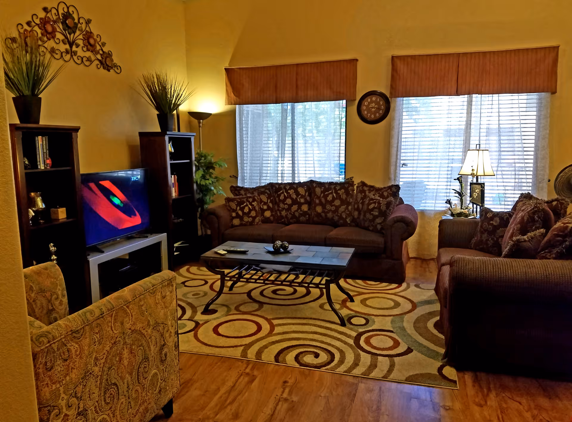 Cozy living room with couches, coffee table, TV, rug, and decorative lighting.