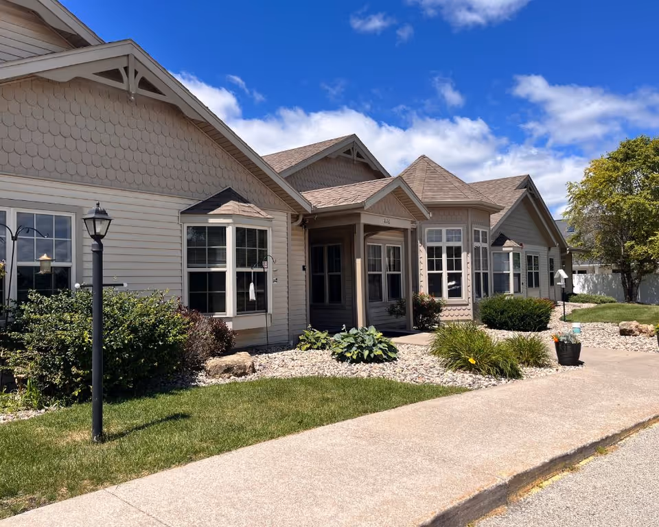 Front view of a senior living facility with light-colored homes and landscaped shrubs
