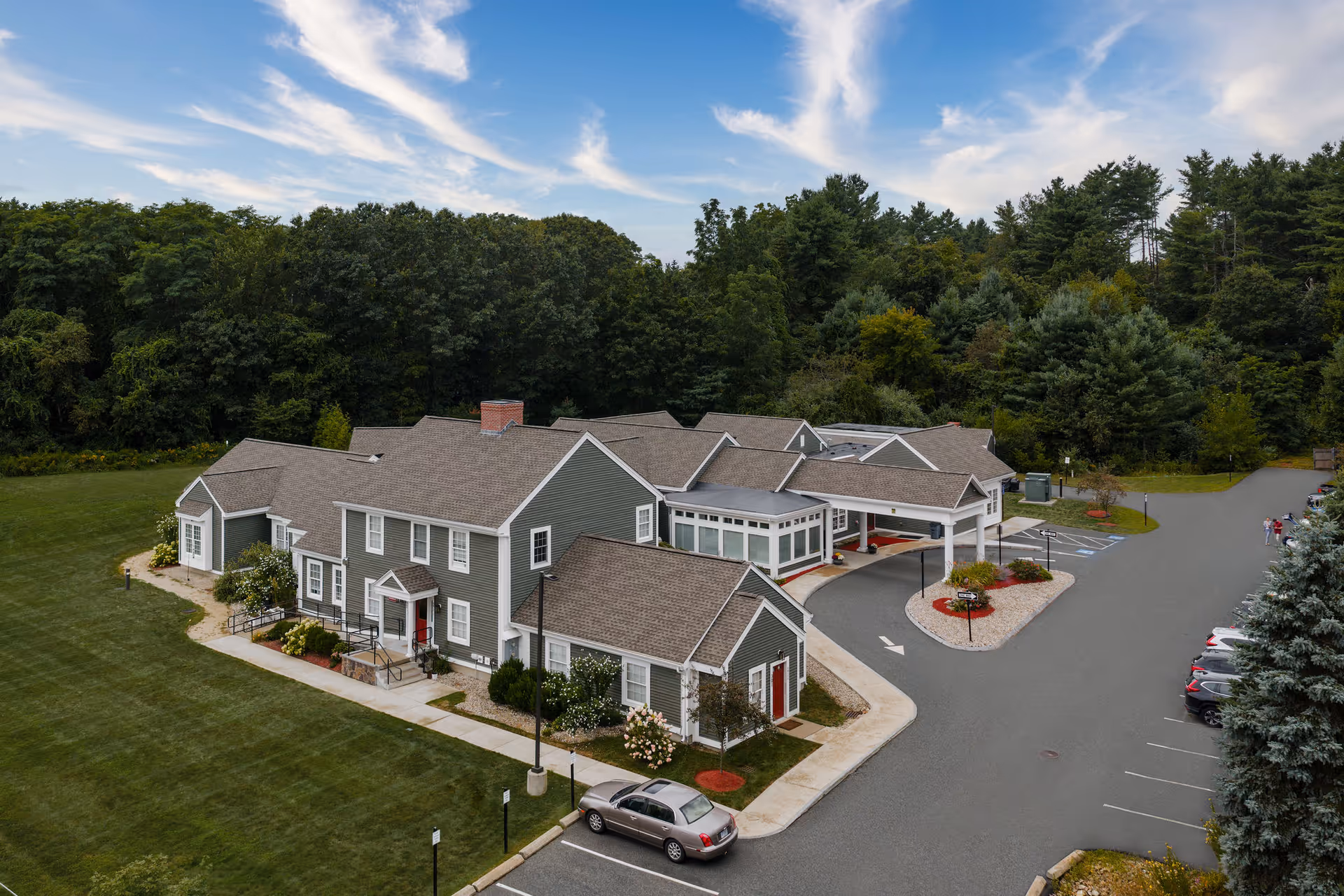 Exterior view of Johnson Creek Village senior living with parking and surrounding woods.