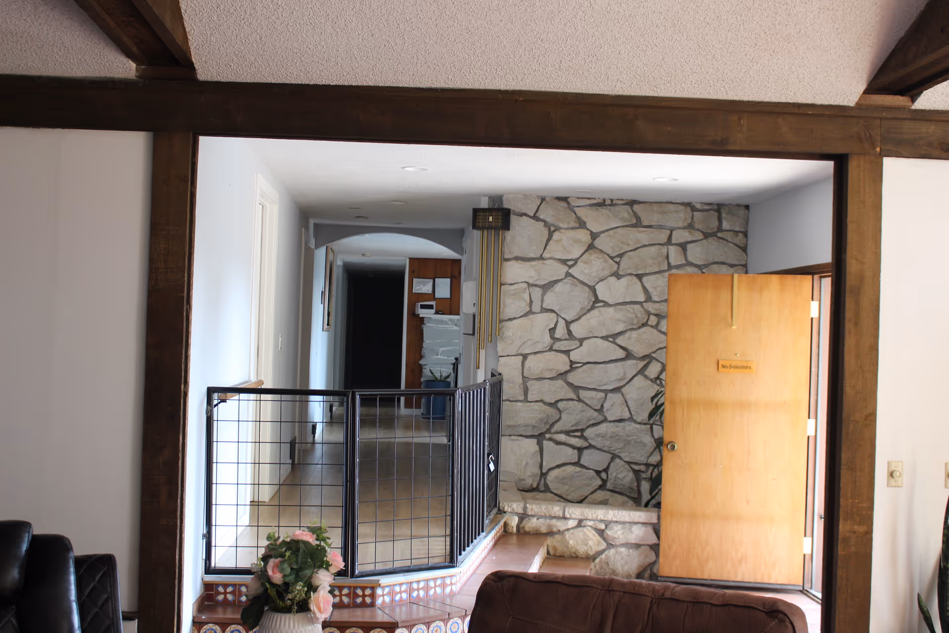 Interior hallway with stone accent wall, doorway, and metal railing.