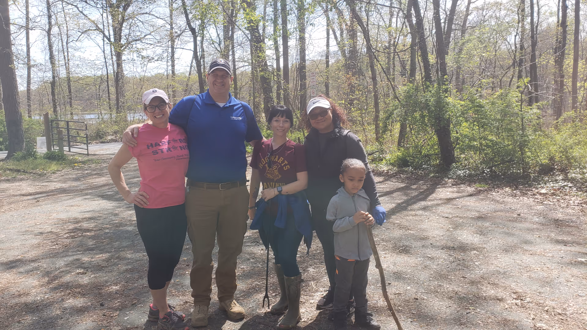 Group of five people posing outdoors in a wooded area.
