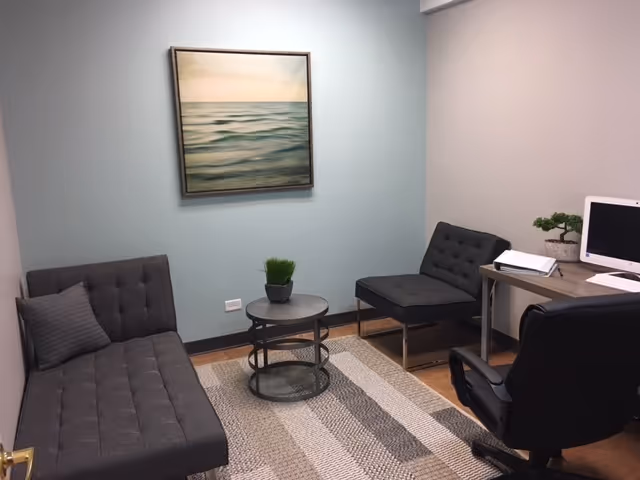 A small lounge area at 7 Hills Healthcare Center with two gray couches, a coffee table.