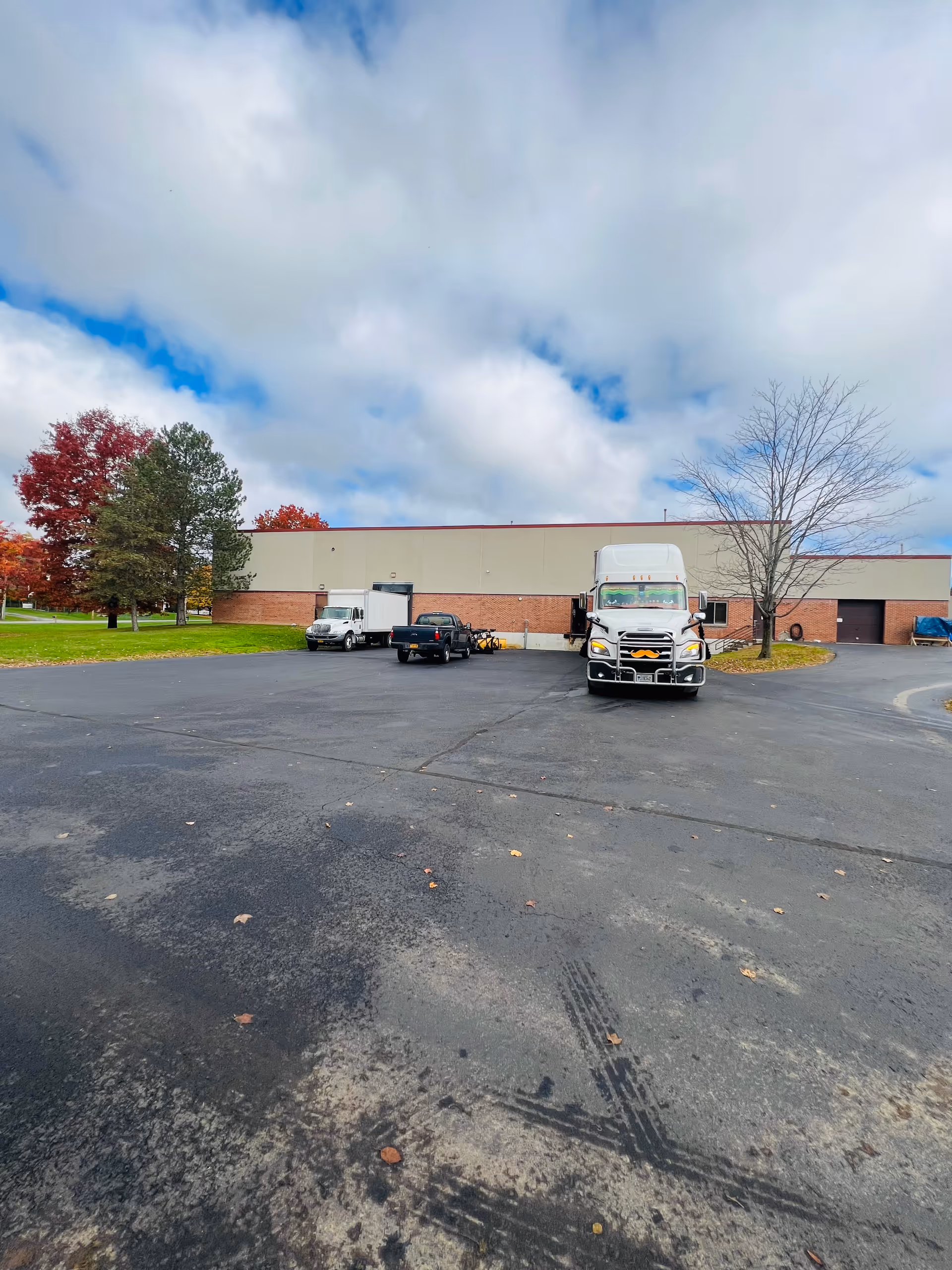 Exterior view of a large facility with trucks parked in a spacious lot.