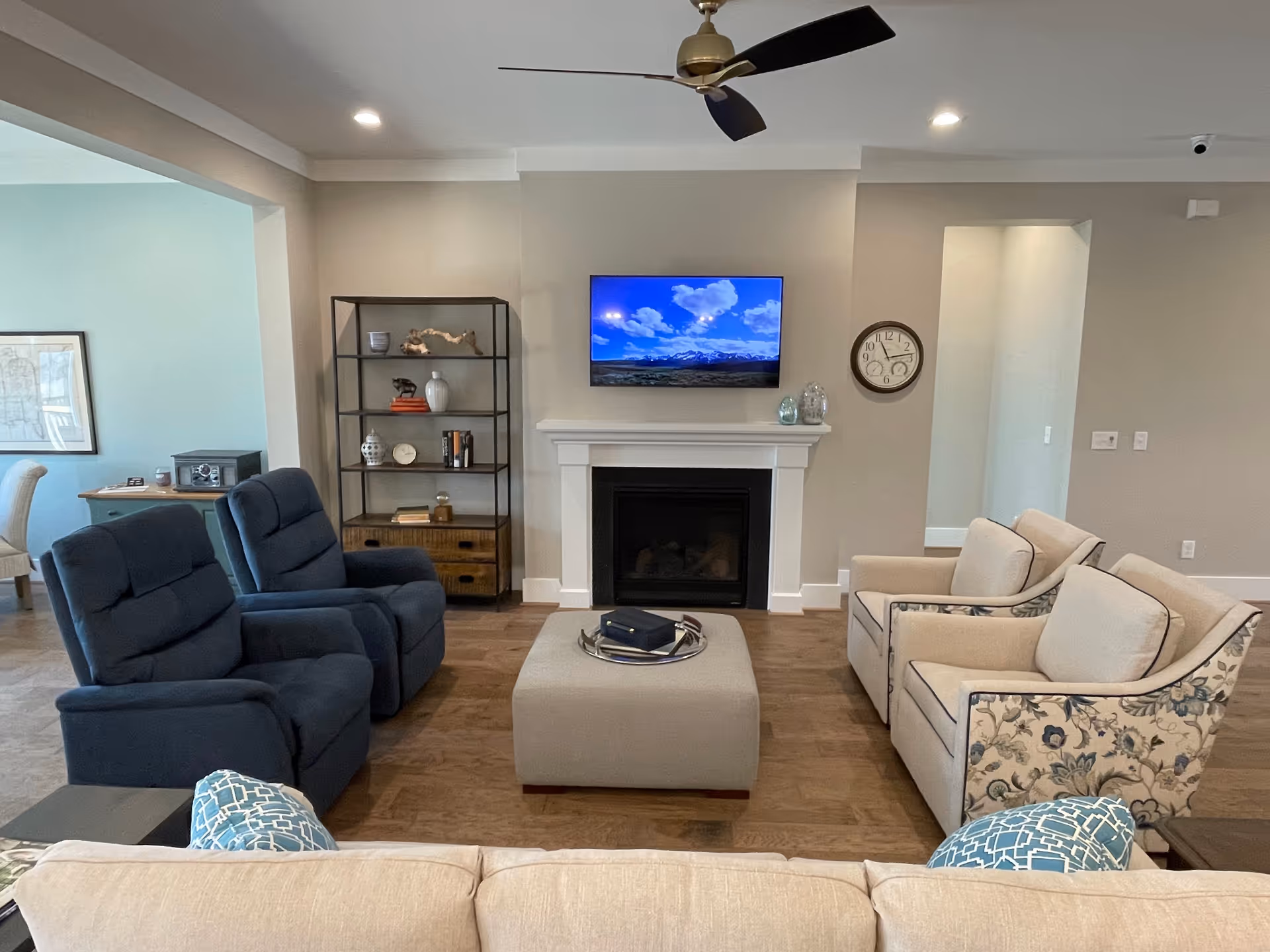 A modern living room with a fireplace, mounted TV, shelves, and upholstered seating.
