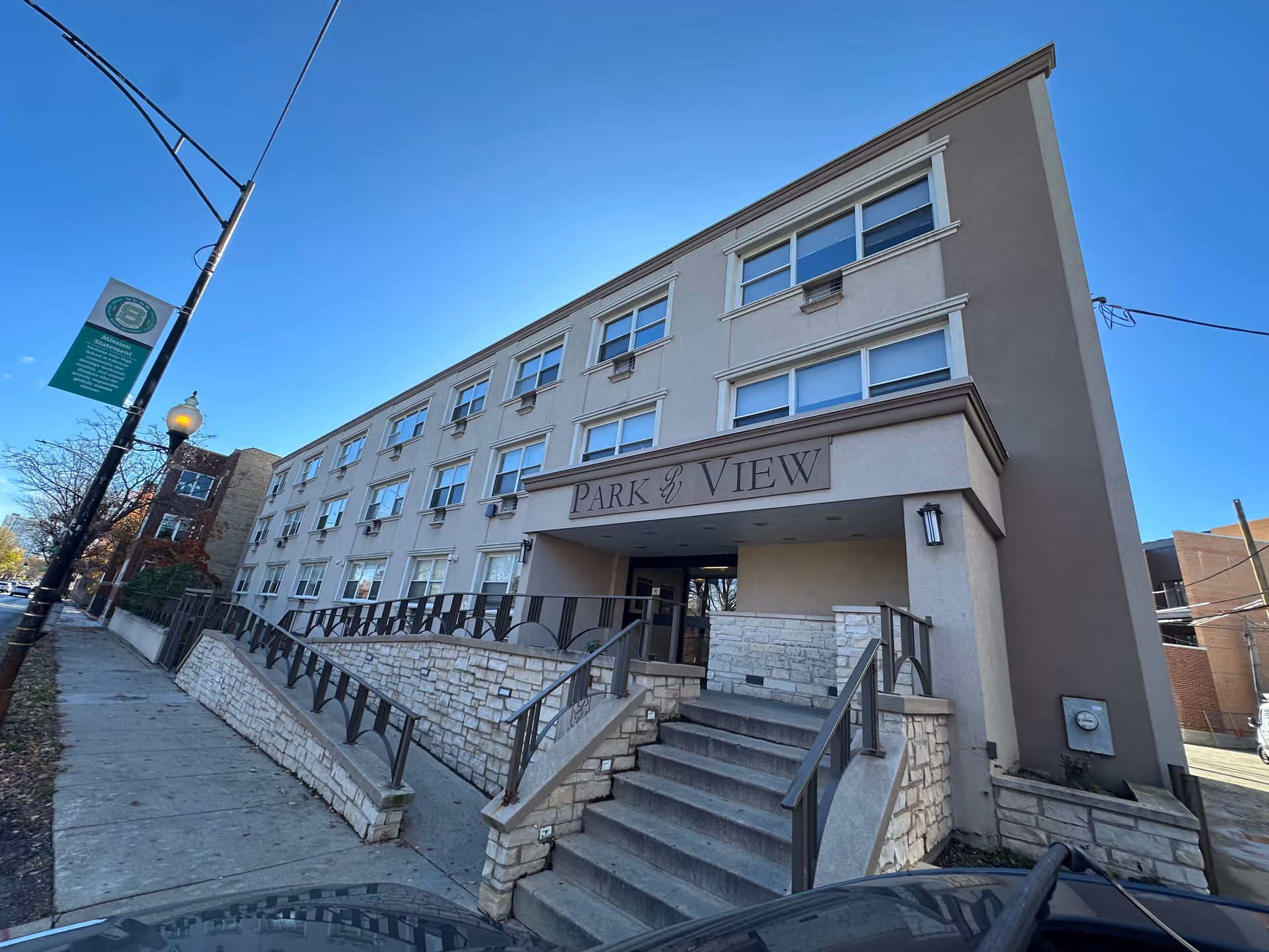 Front entrance of a multi-story building labeled "Park View" with stairs and a ramp leading up from the sidewalk.