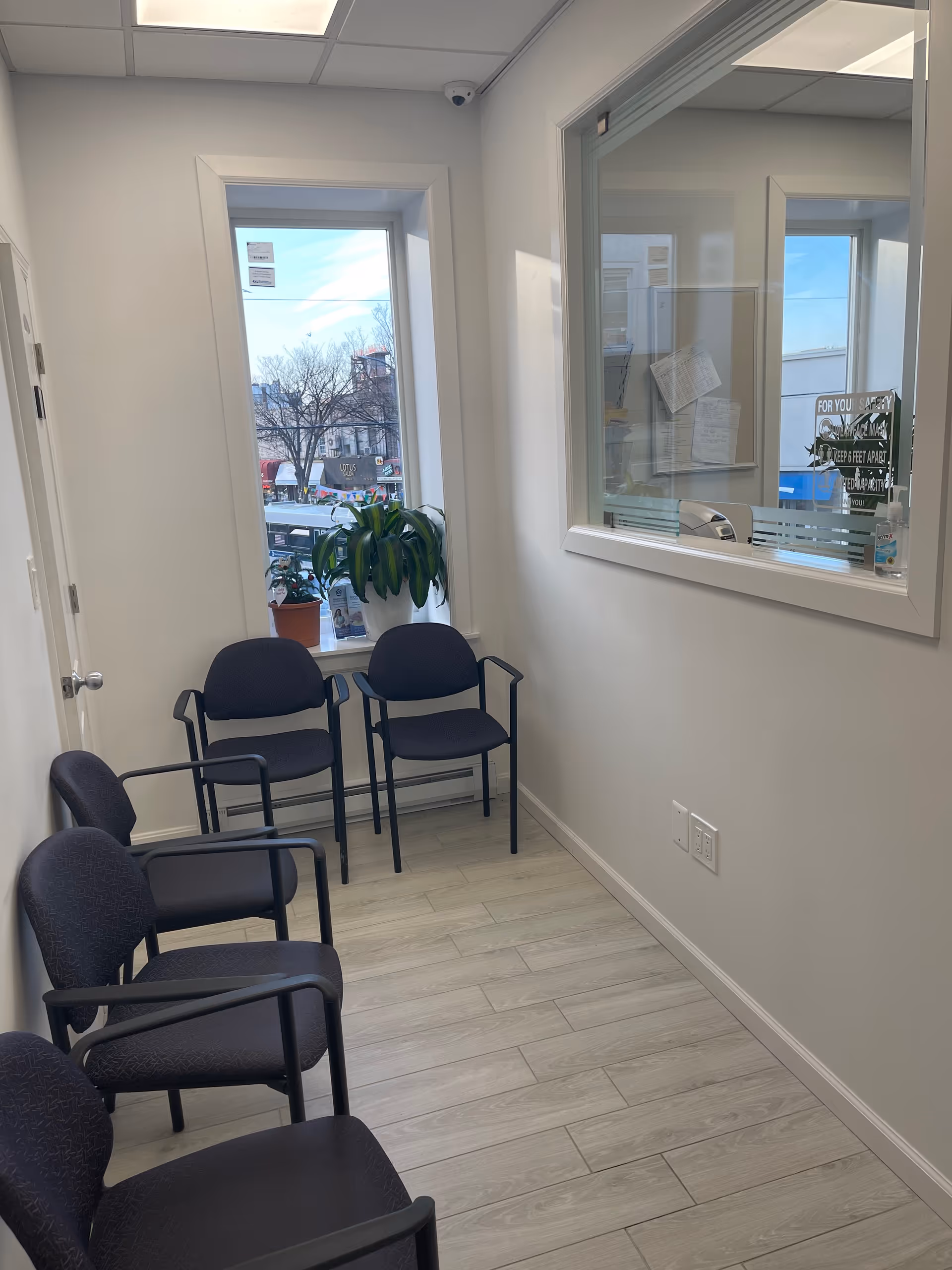 Small indoor waiting area with dark chairs along wall and a potted plant by the window.