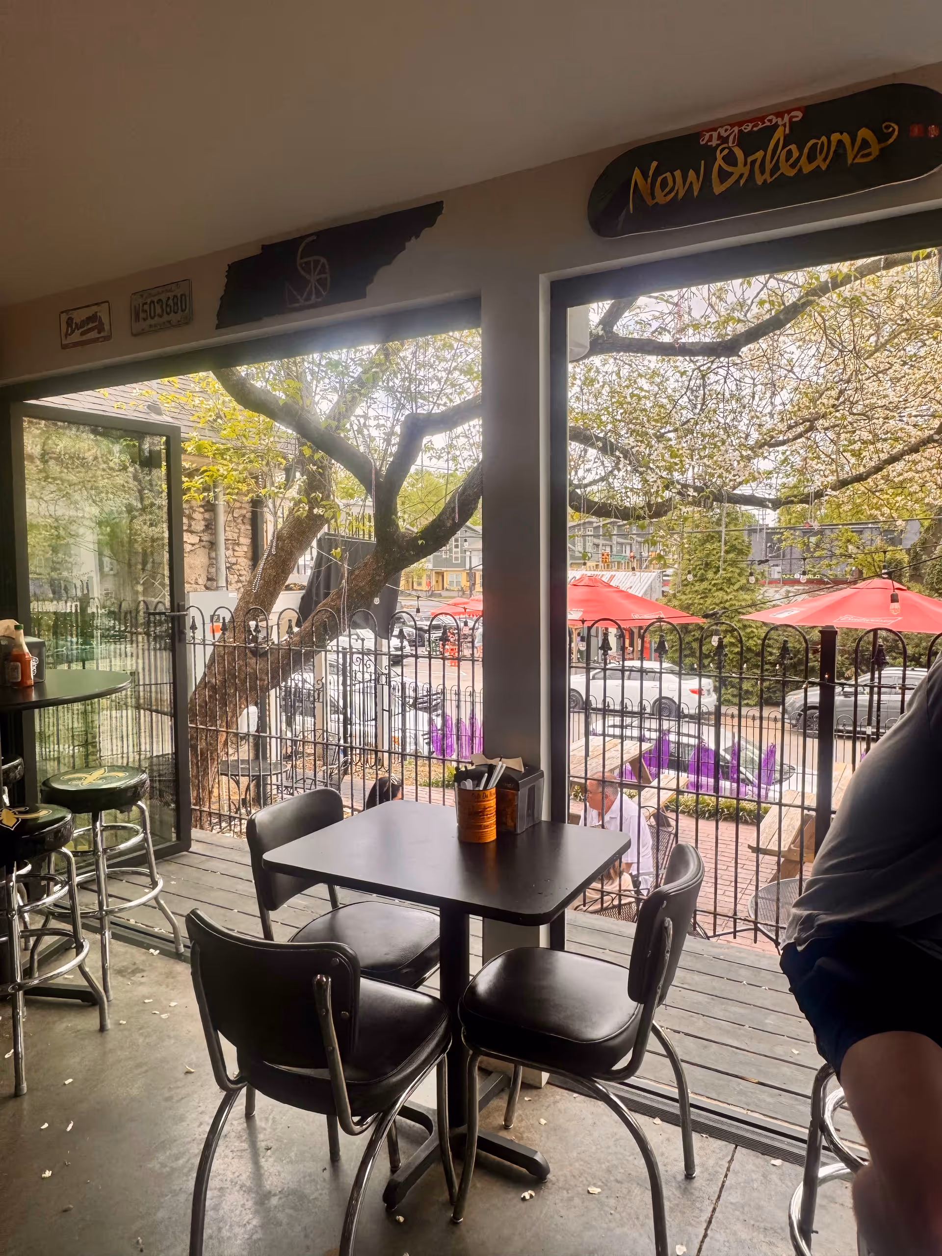 Indoor dining area with a black table, chairs, and large windows overlooking outdoor patio