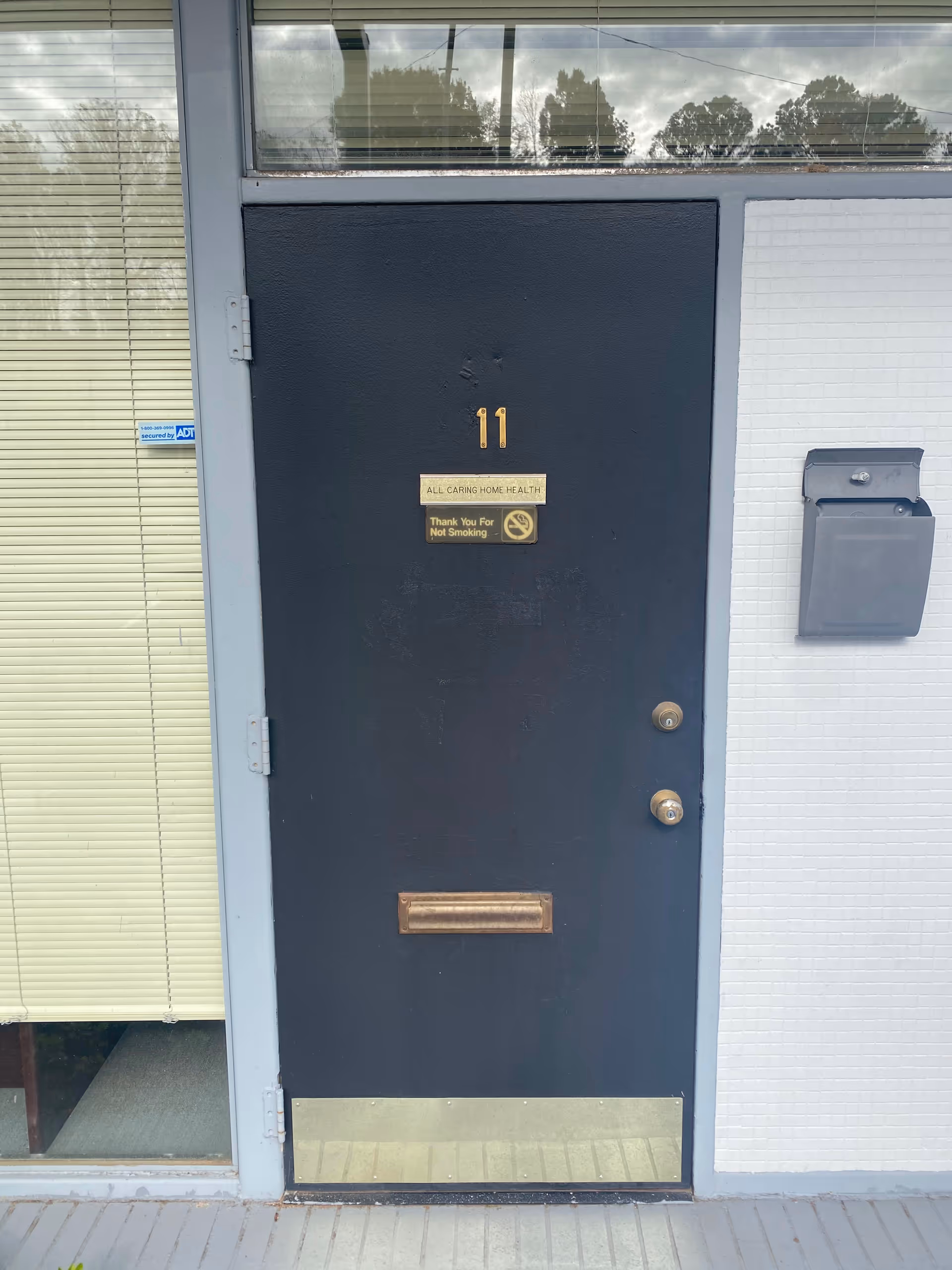 Dark blue exterior door with the number 11 and All Caring Home Health plaque.
