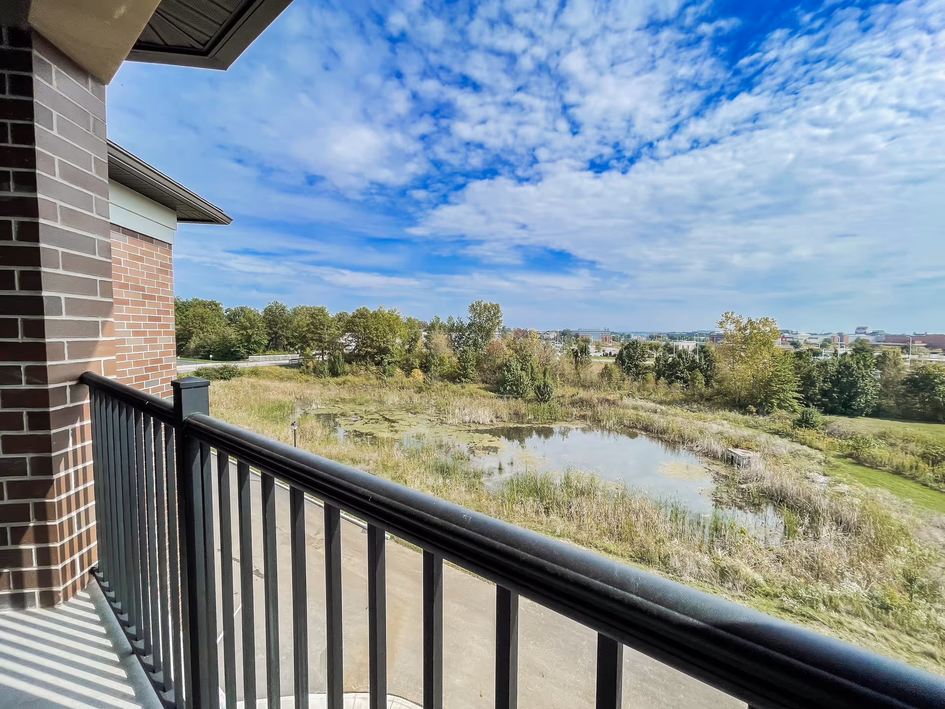 Balcony view from a Polaris Community building overlooking a pond and open fields.