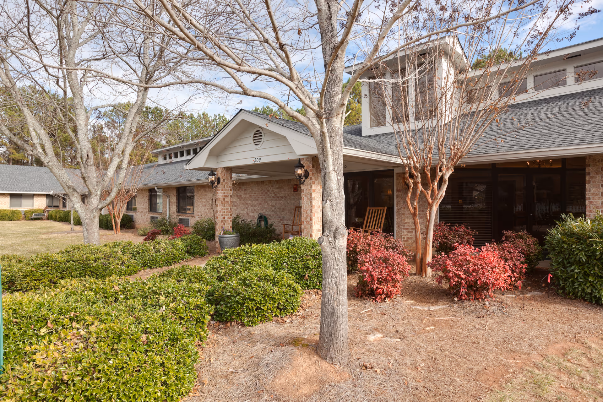 Exterior view of Oaks Scenic View Assisted Living with brick building and landscaped entrance.