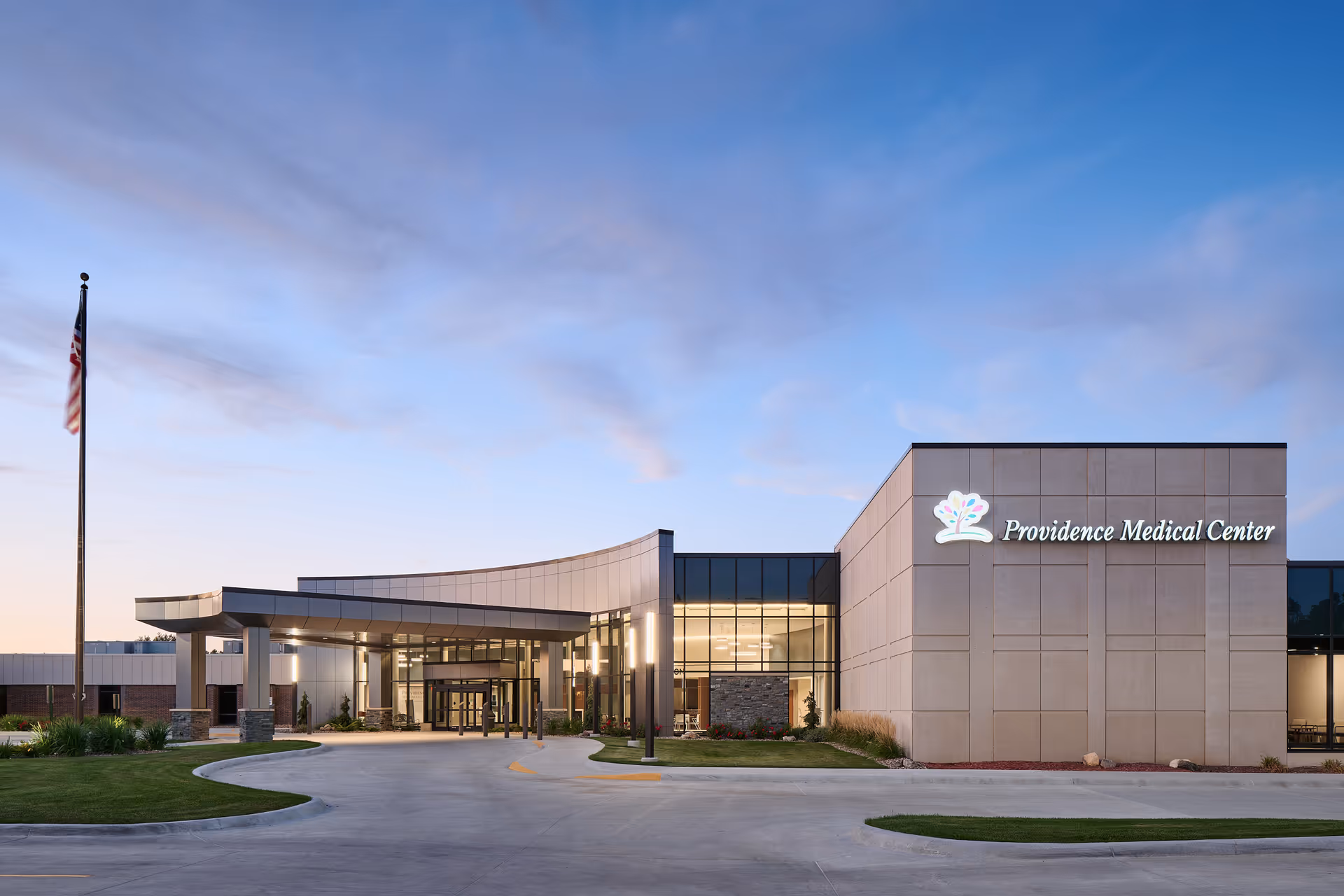 Exterior view of Providence Medical Center Nebraska with a glass entry and flagpole