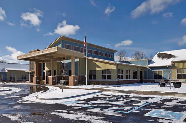 Exterior view of The Springs of Mooresville senior living facility with a snow-covered parking lot.