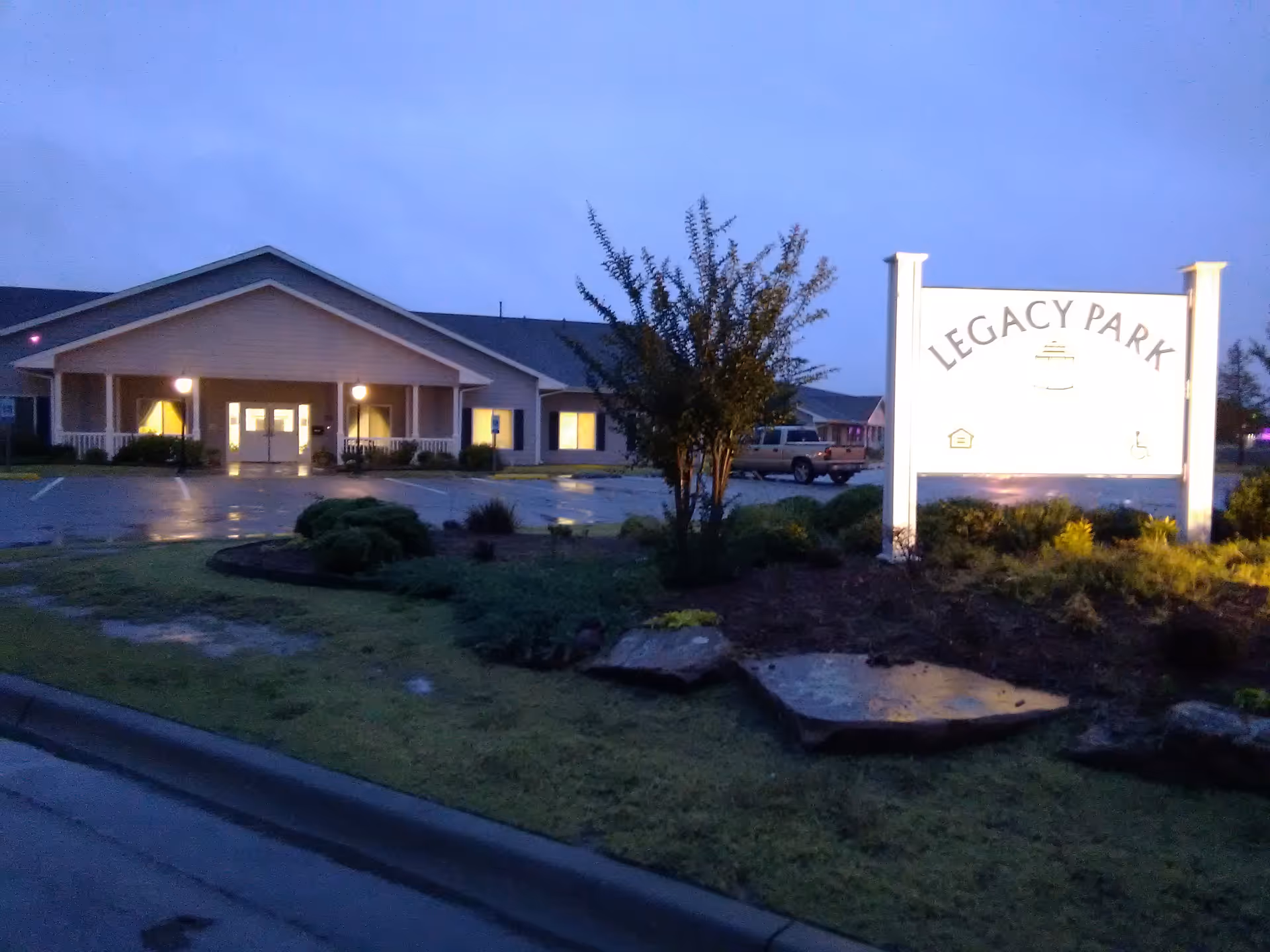 Exterior of Legacy Park with a lit front sign and landscaping.