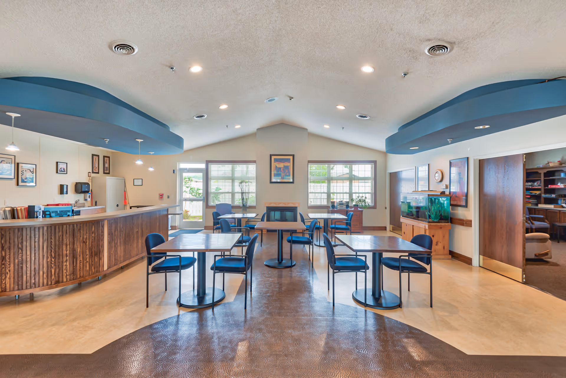 Interior common area with a wooden front desk, tables, blue accents, and an aquarium.
