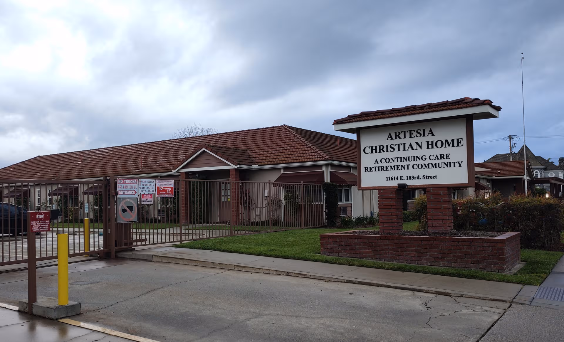 Exterior view of Artesia Christian Home with gated entrance and sign.