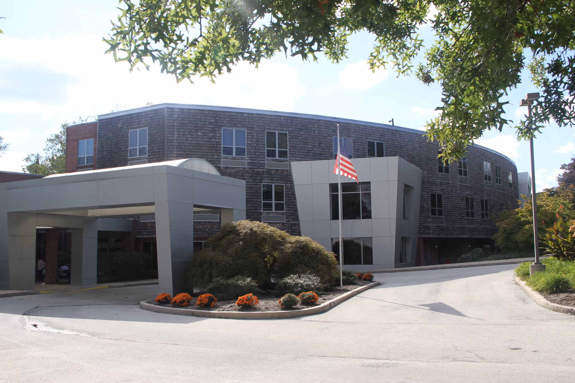 Modern senior living facility Springfield Crossings exterior with entrance canopy and flag.
