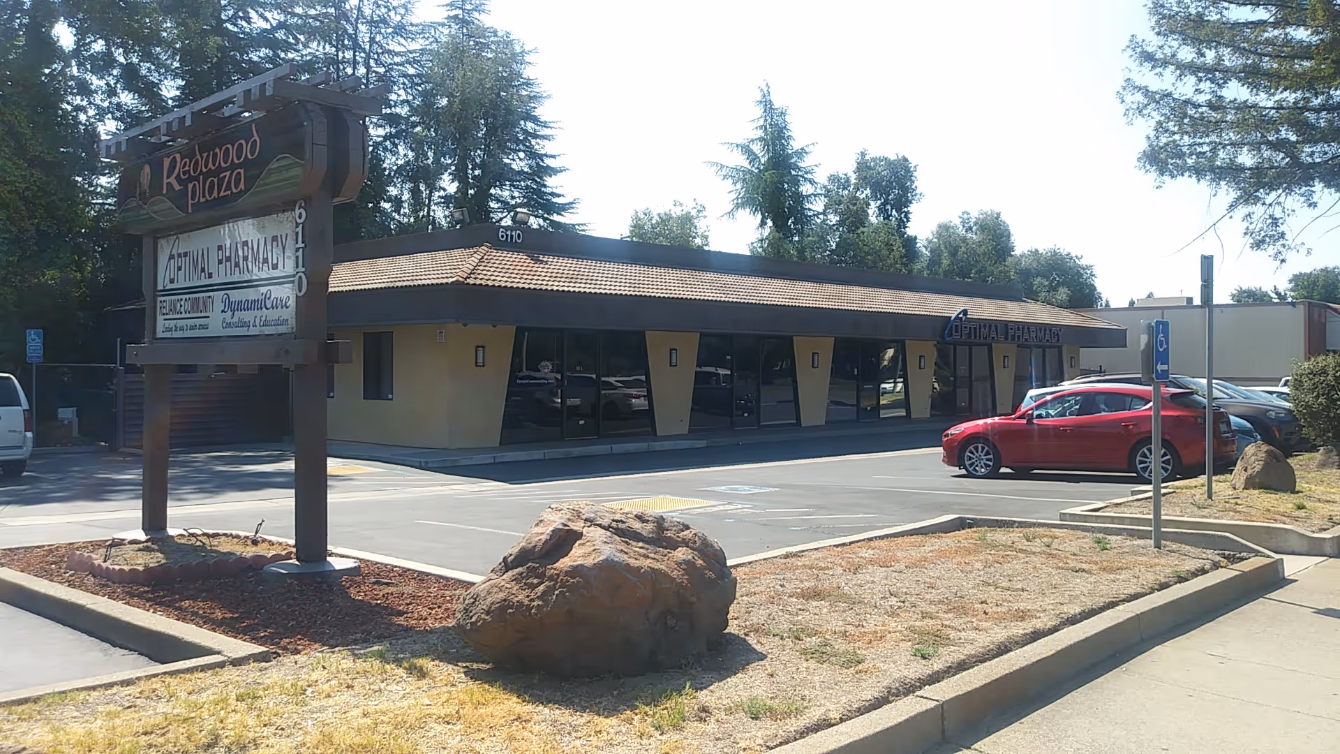 Exterior view of a single-story building with glass windows and a parking lot.