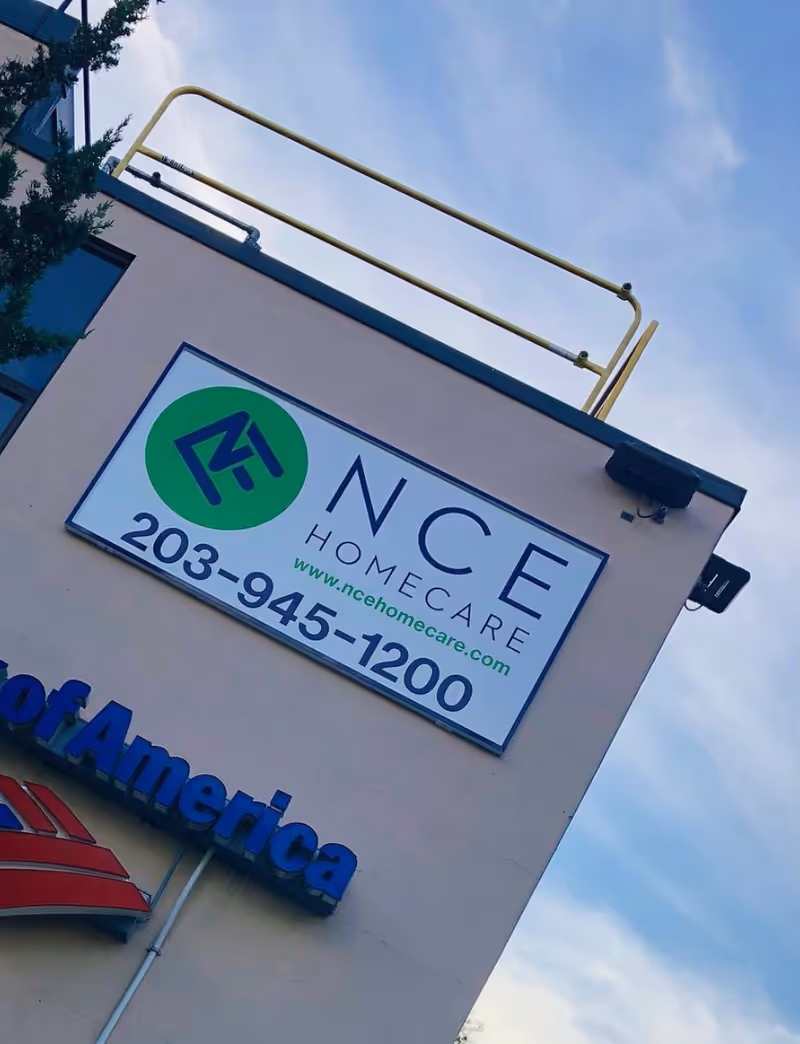 Outdoor building sign reading NCE Homecare on the front of a beige wall.