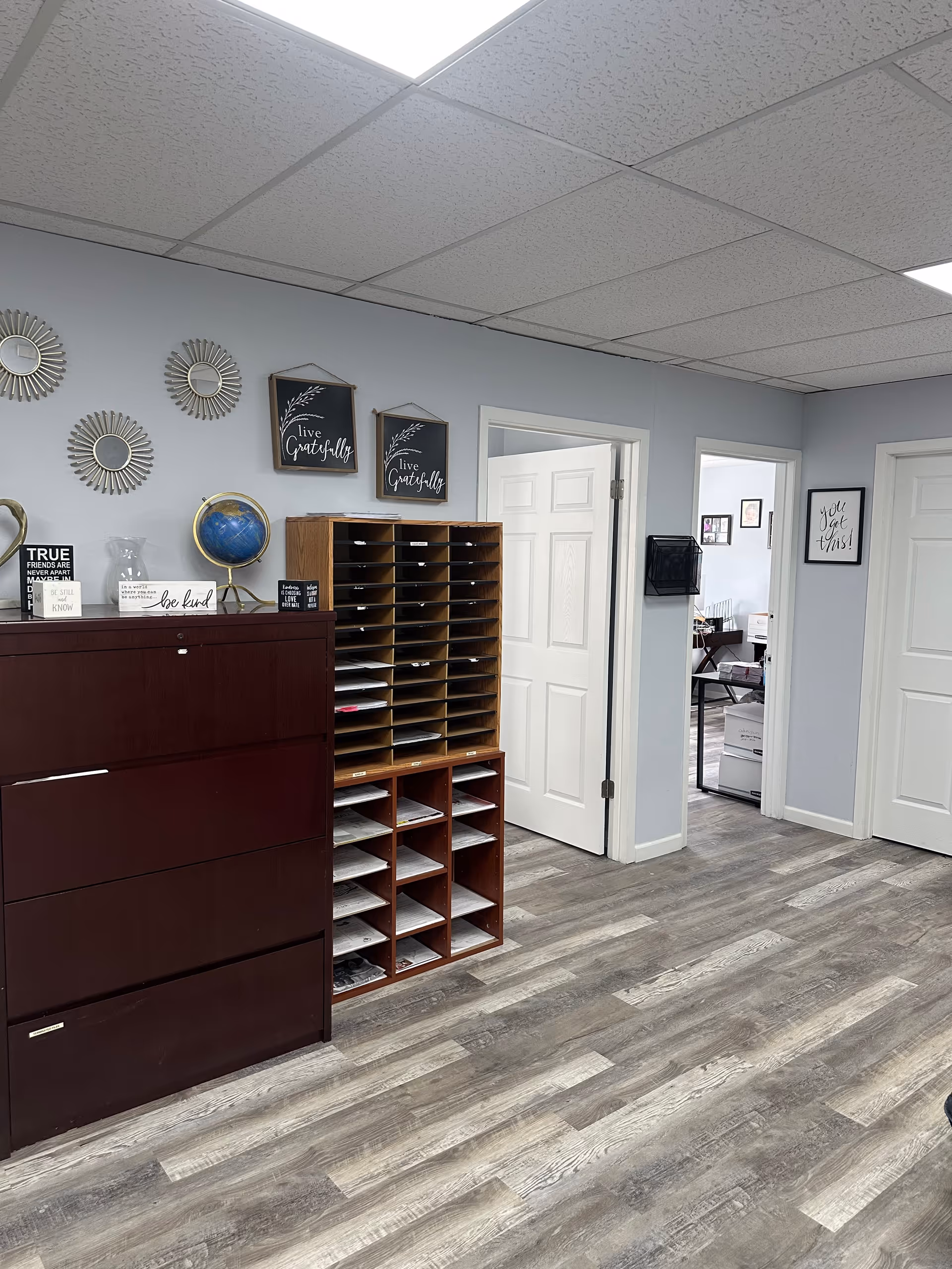 Interior office area with filing cubbies, shelves, wall decor, and two doorways.